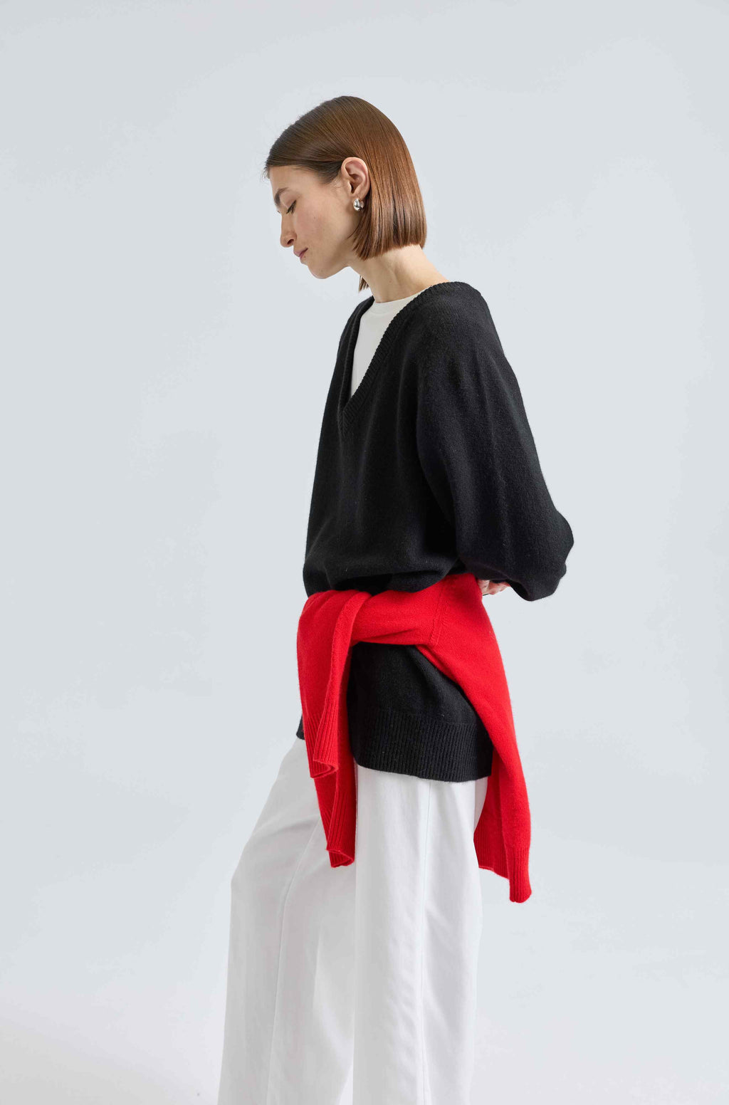 Person wearing a black sweater with a red sweater over it on a white background