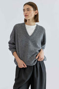 Woman wearing a gray sweater and black pants on a white background