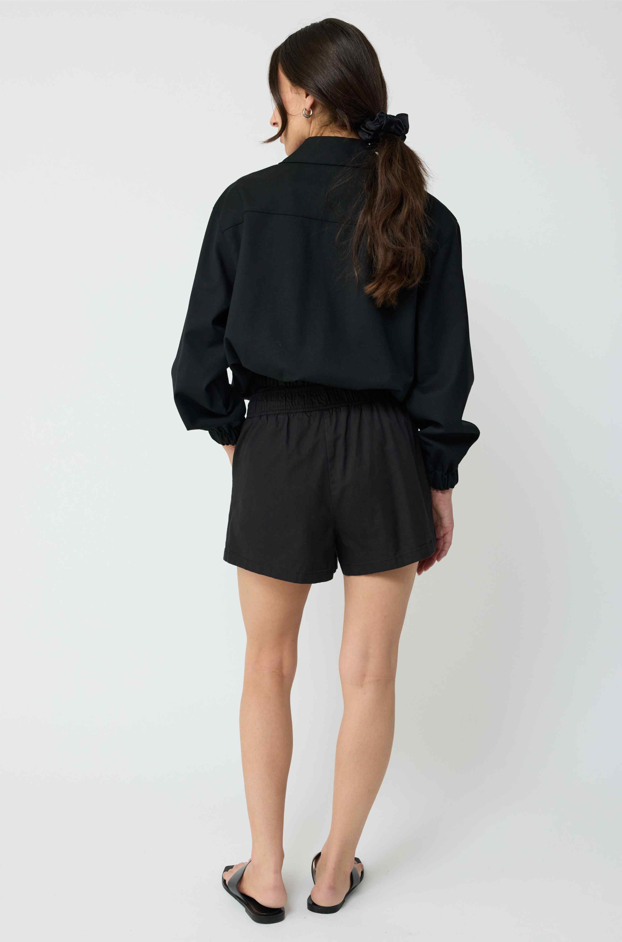 Person wearing a black outfit with shorts on a white background