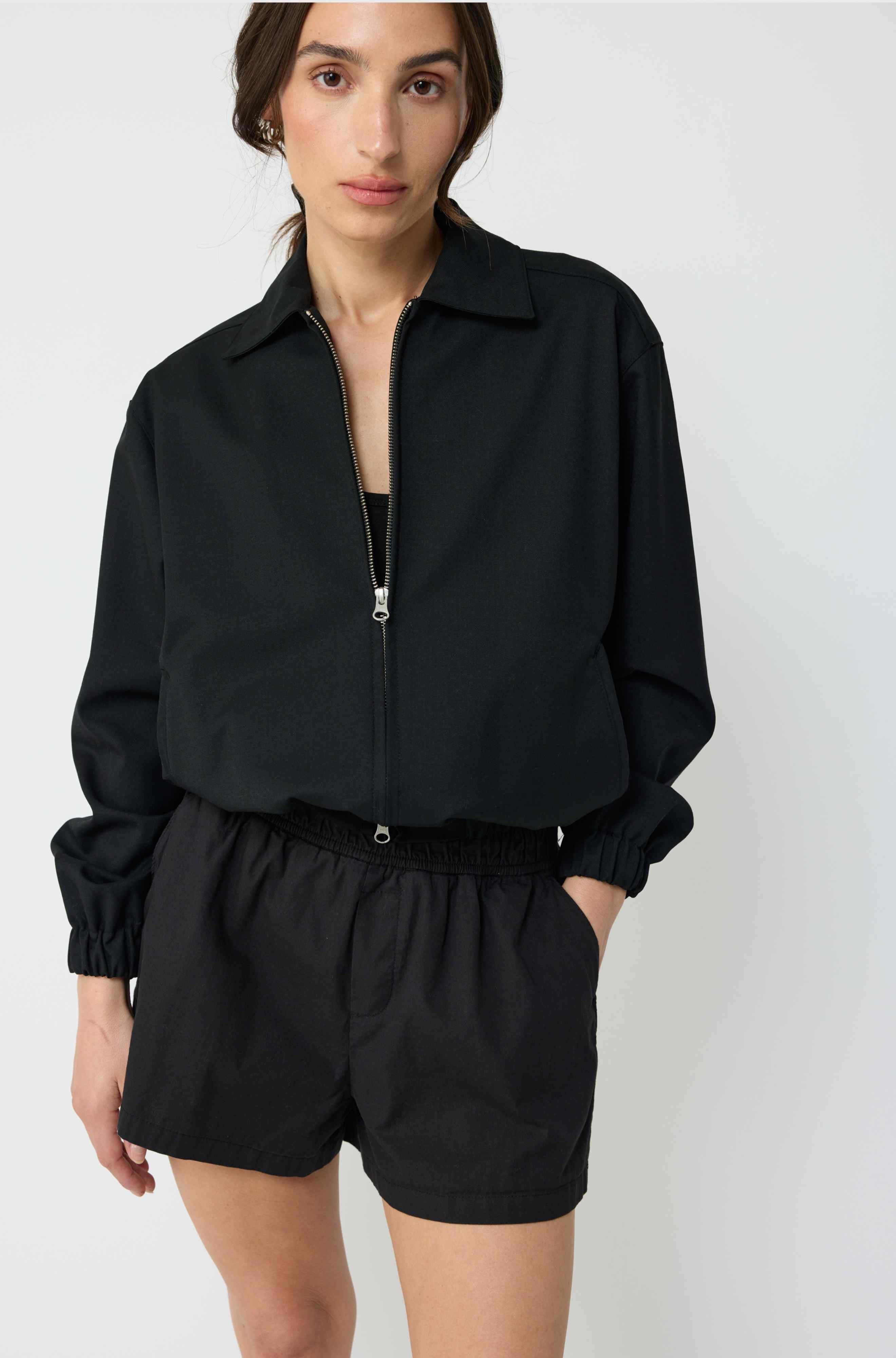 Woman wearing a black jacket and shorts on a white background