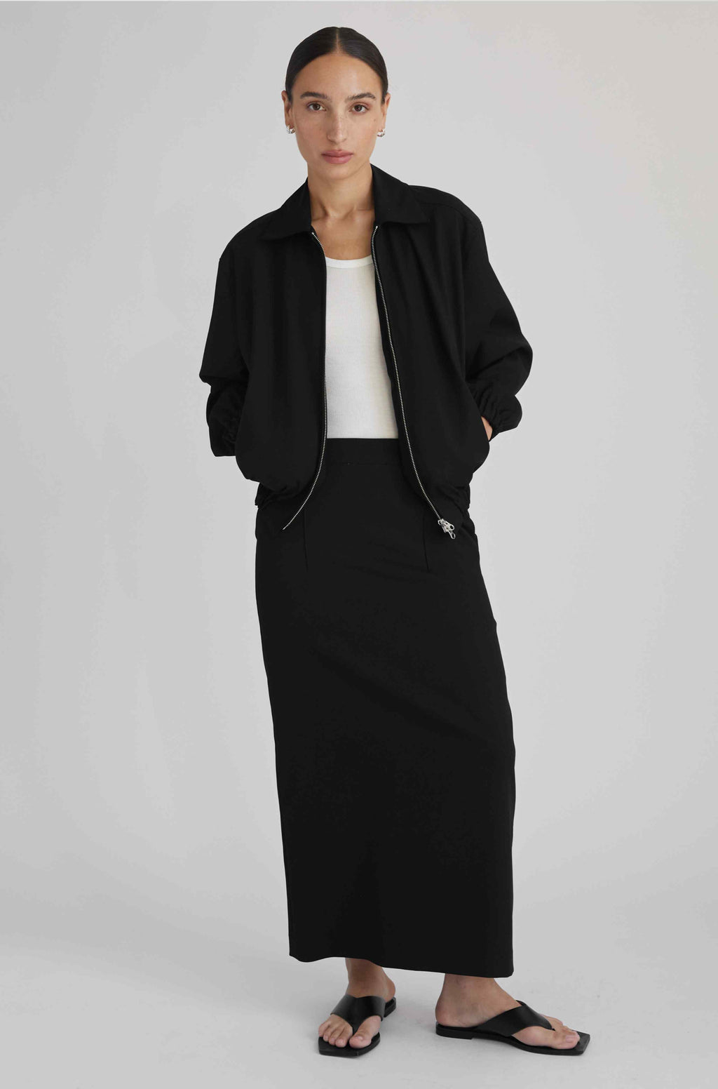 Woman wearing a black jacket and black skirt on a white background