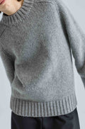Gray knitted sweater worn by a person on a light gray background