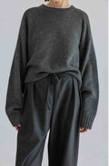 Person wearing a dark gray sweater and matching pants on a light gray background