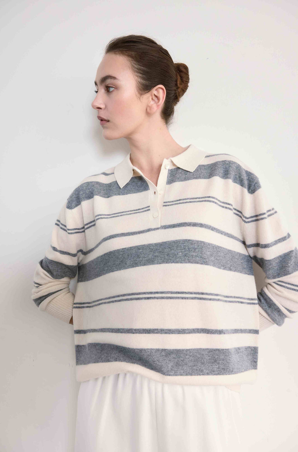 Woman wearing a striped sweater and white shirt against a plain background