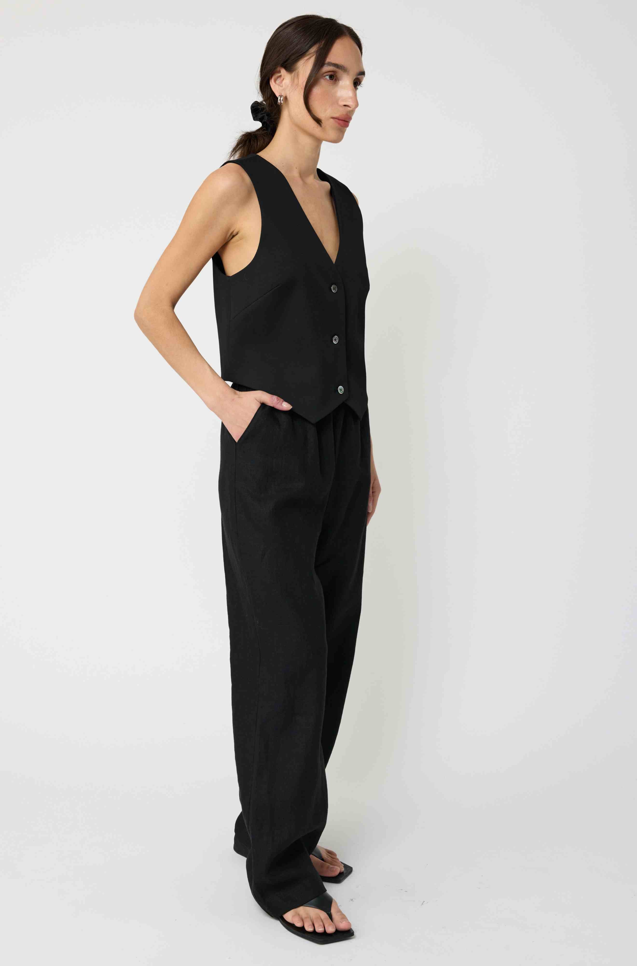 Woman wearing a black sleeveless top and pants on a white background