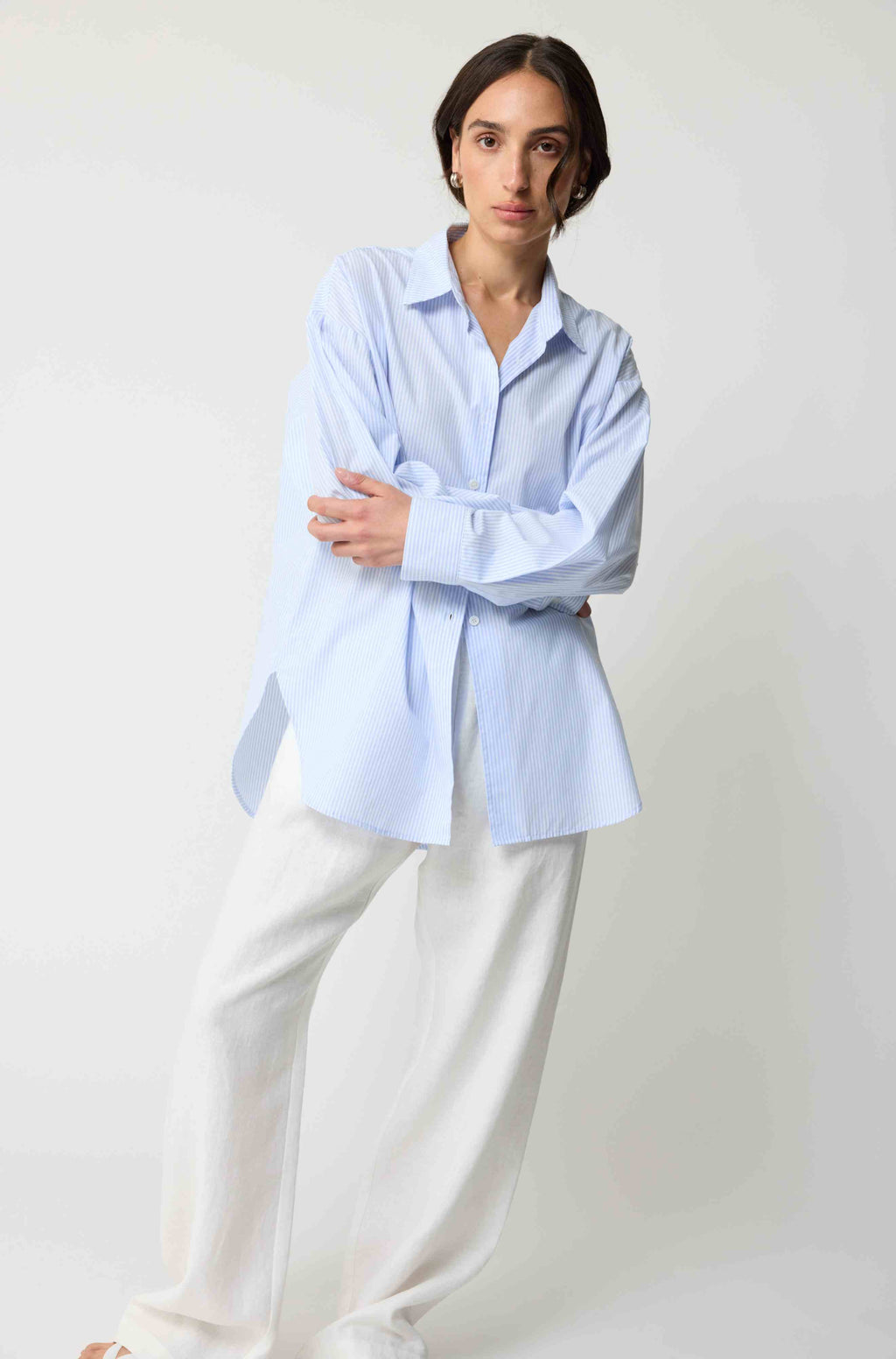 Person wearing a light blue shirt and white pants on a plain background
