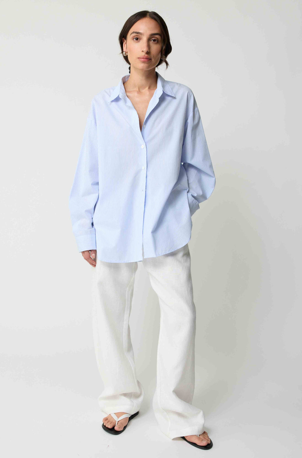 Person wearing a light blue shirt and white pants on a plain background