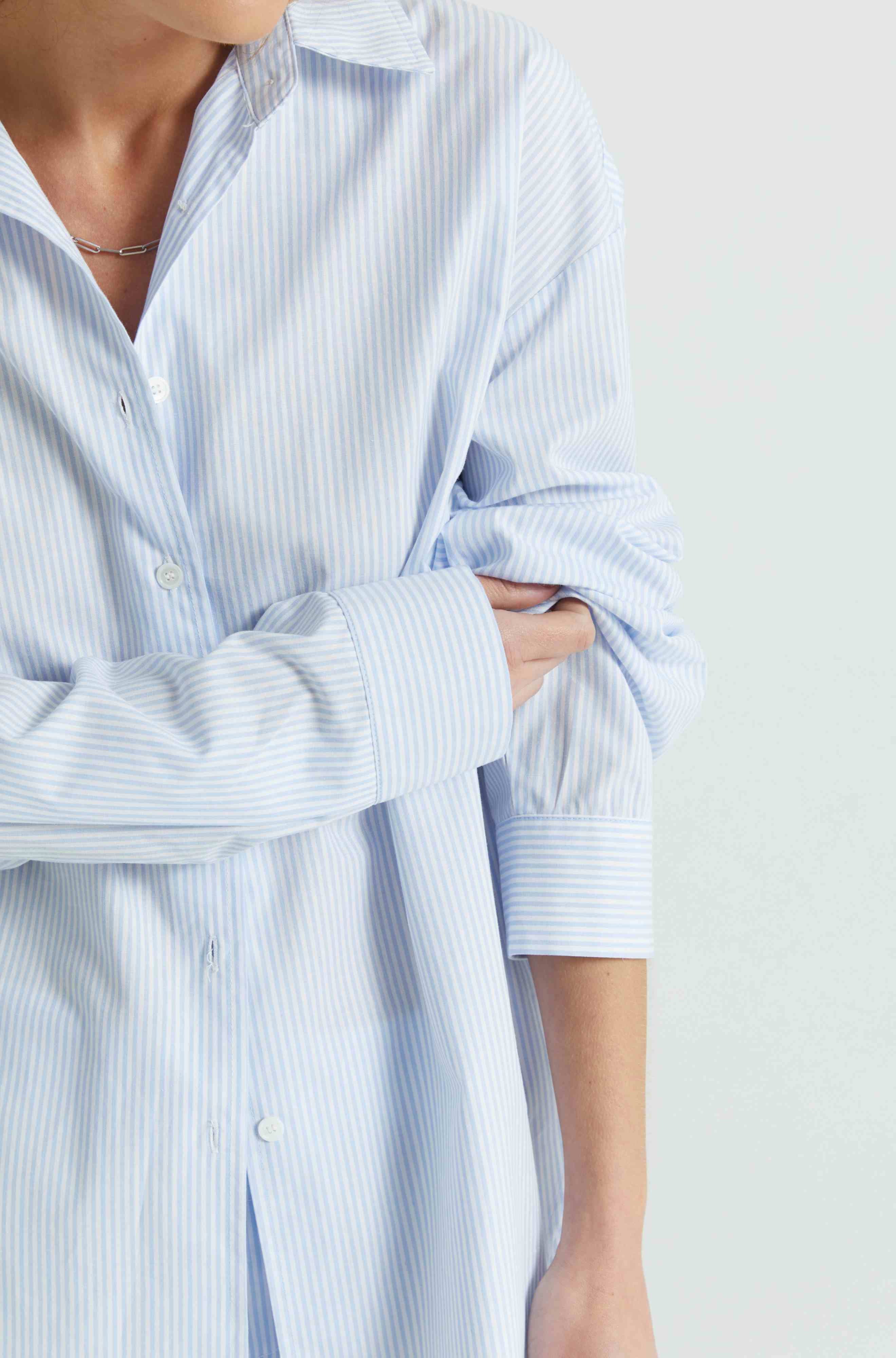 Person wearing a light blue and white striped shirt on a plain background