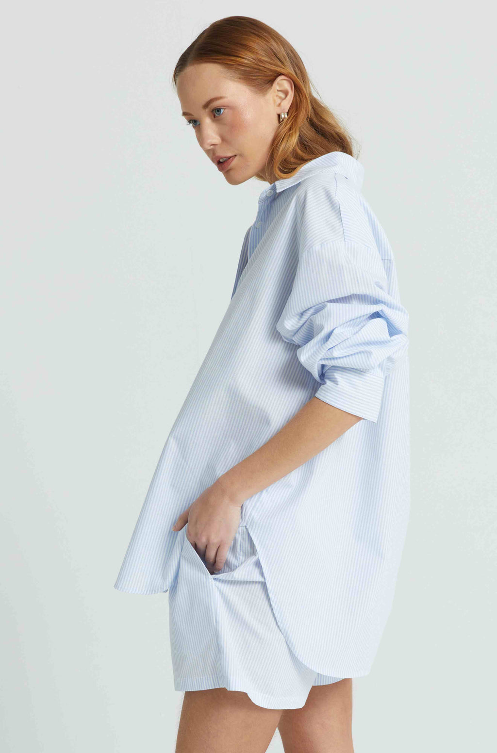 Woman wearing a light blue oversized shirt on a white background