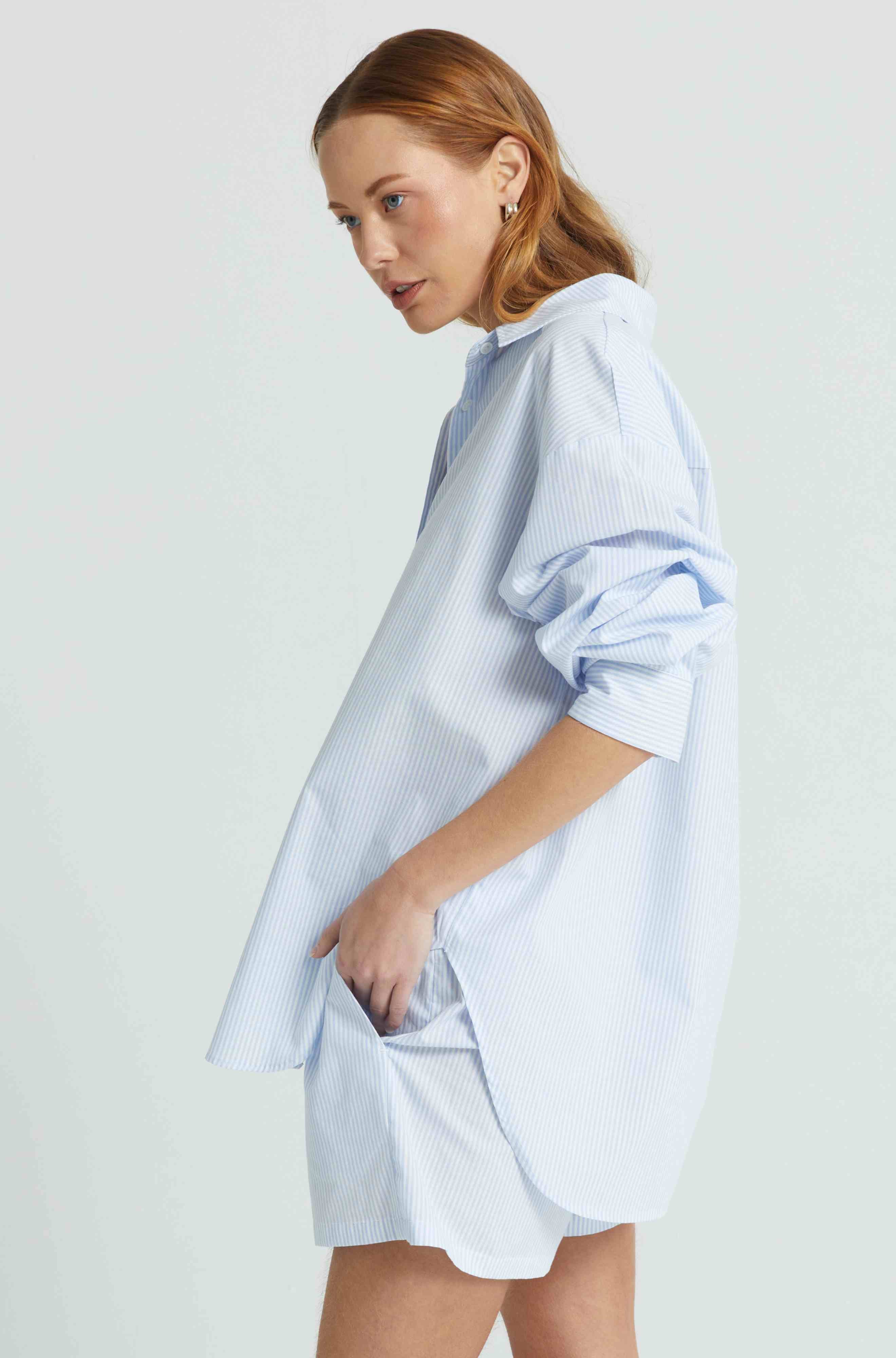 Woman wearing a light blue oversized shirt on a white background