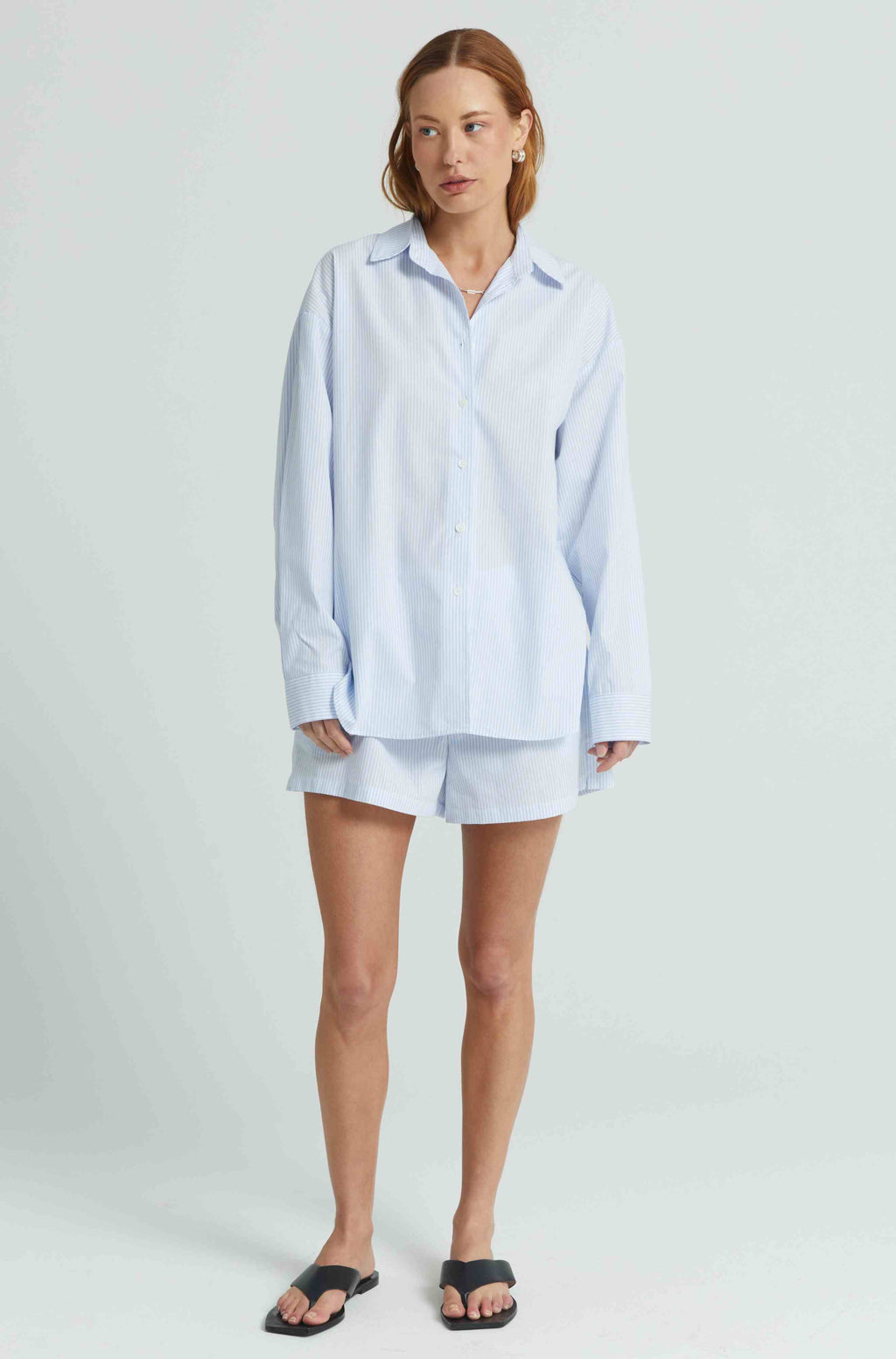 Woman wearing a light blue shirt and shorts on a white background
