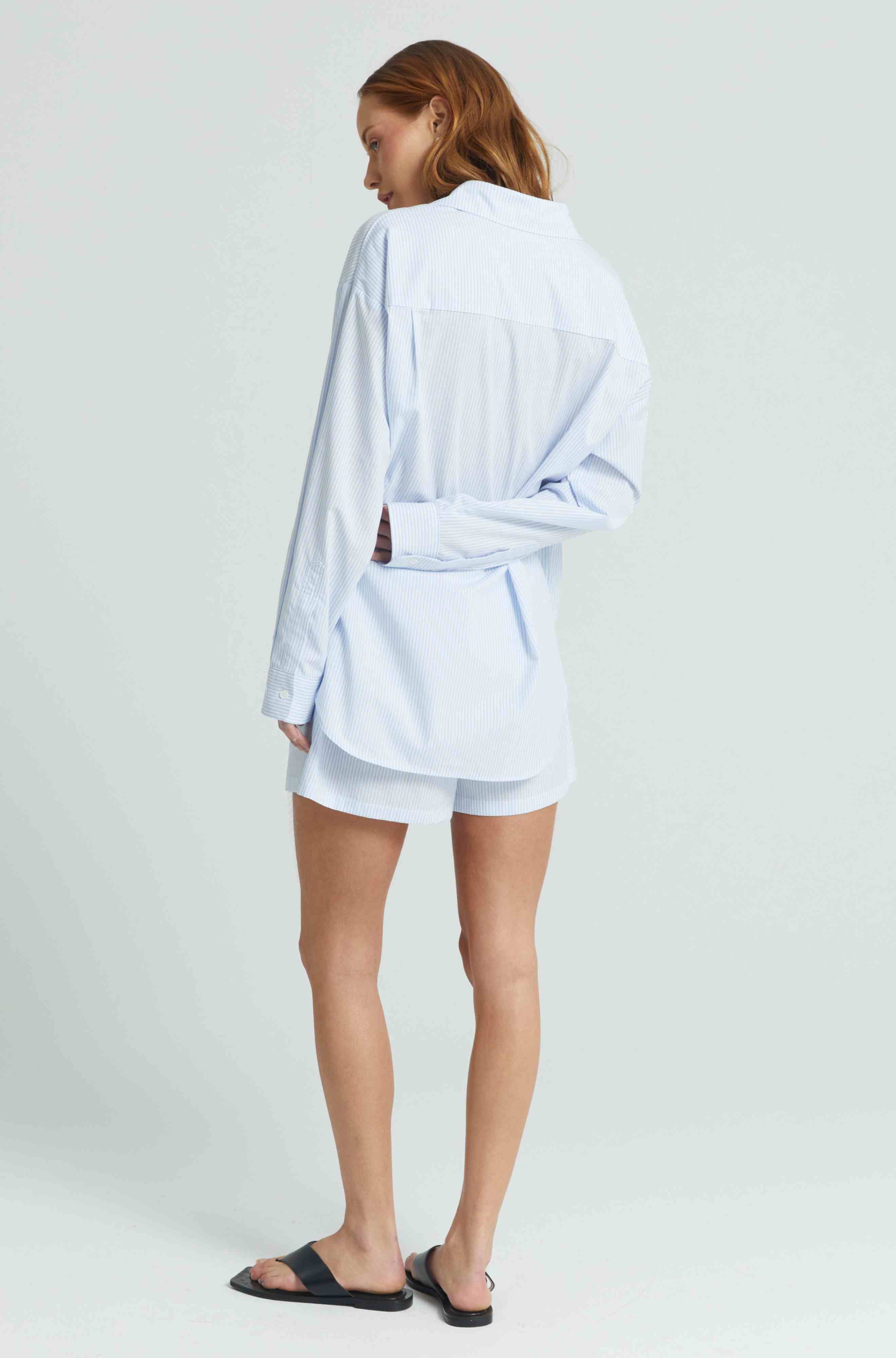 Person wearing a light blue striped outfit on a white background