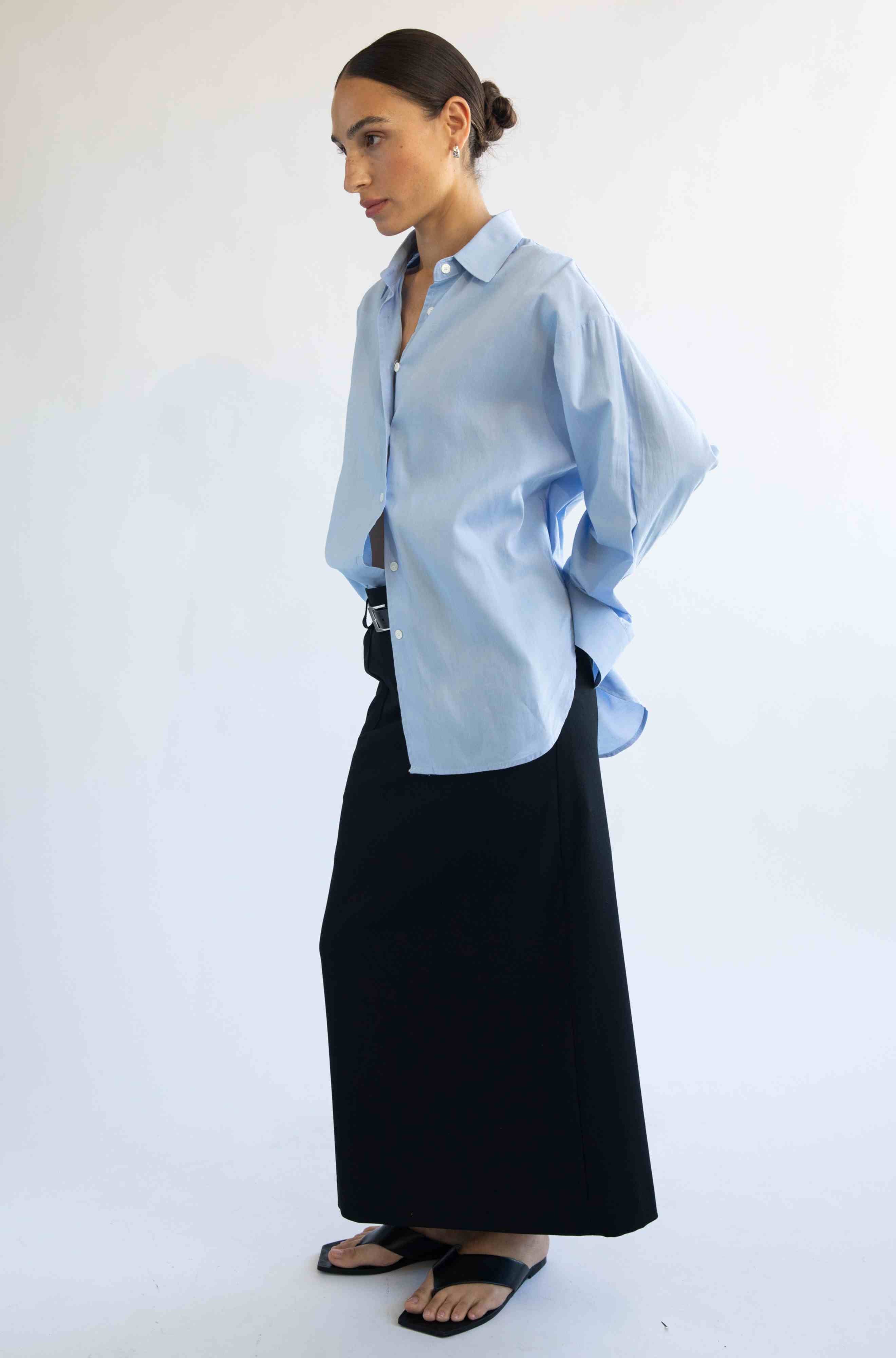 Woman wearing a light blue shirt and black skirt on a white background
