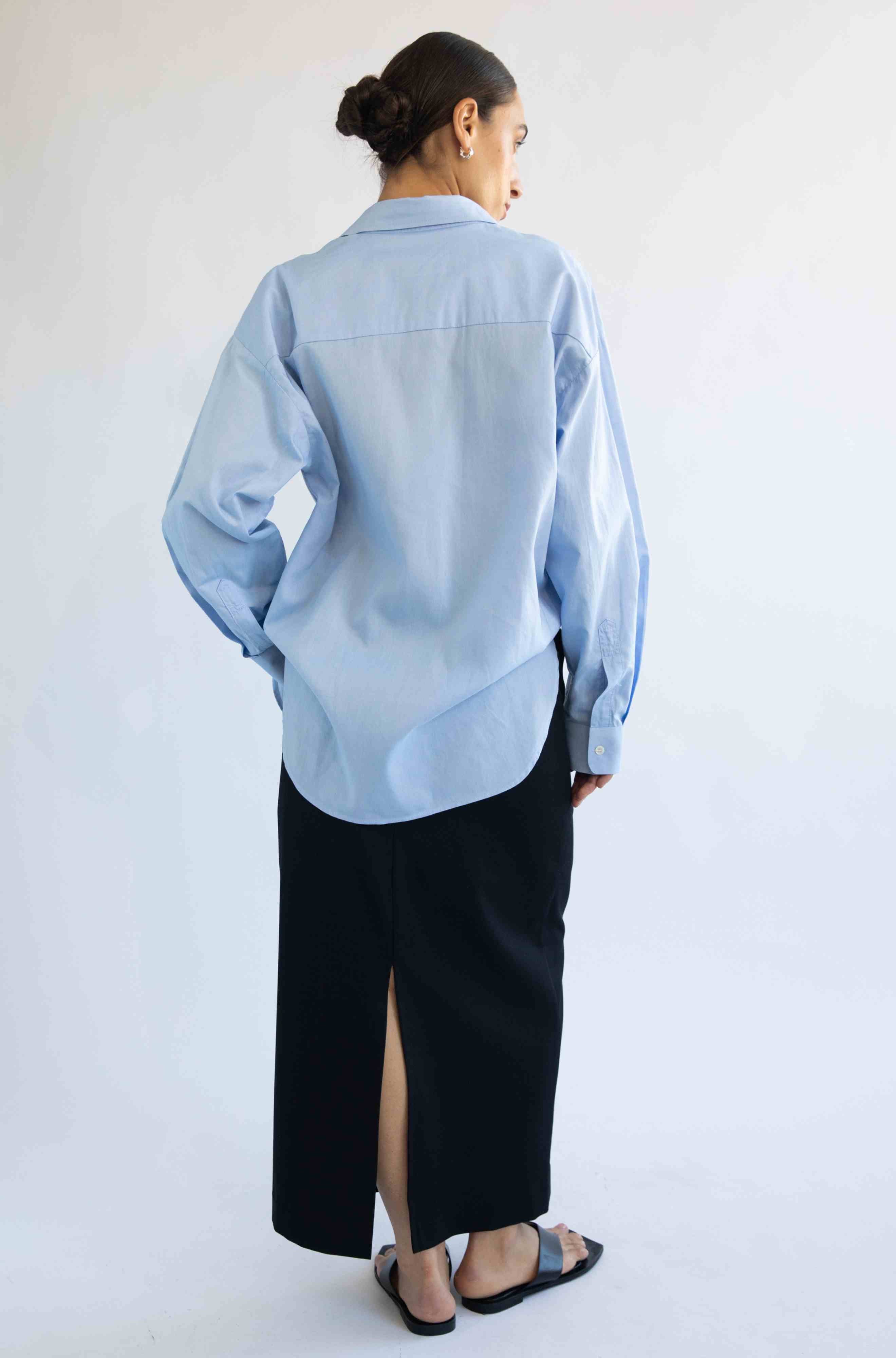 Person wearing a light blue shirt and black pants on a white background