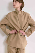 Woman wearing a beige suit against a white background