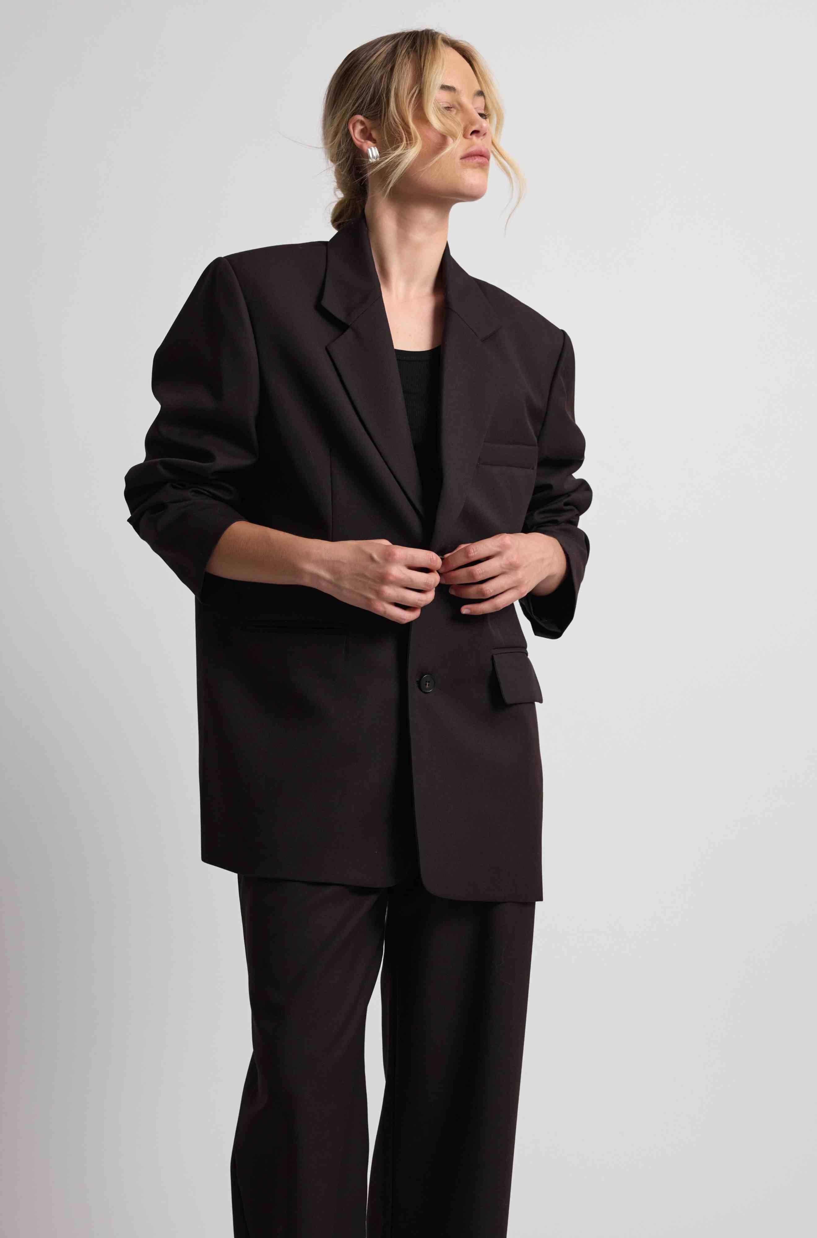 Person wearing a dark brown suit on a plain background