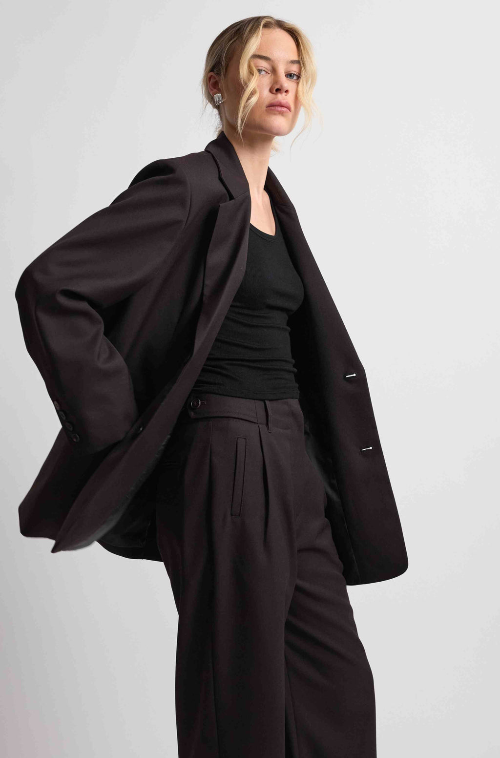 Person wearing a dark brown coat and pants on a light gray background
