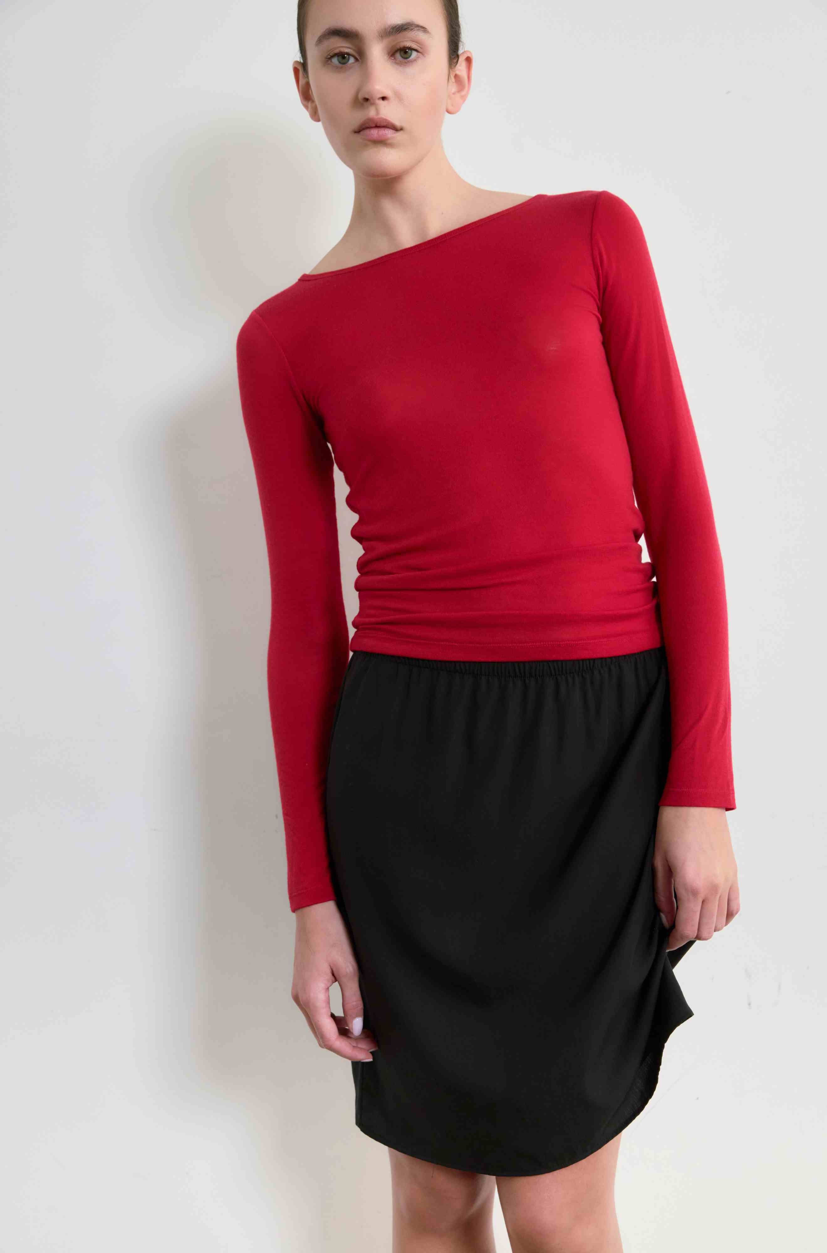 Woman wearing a red long sleeve shirt and black midi skirt