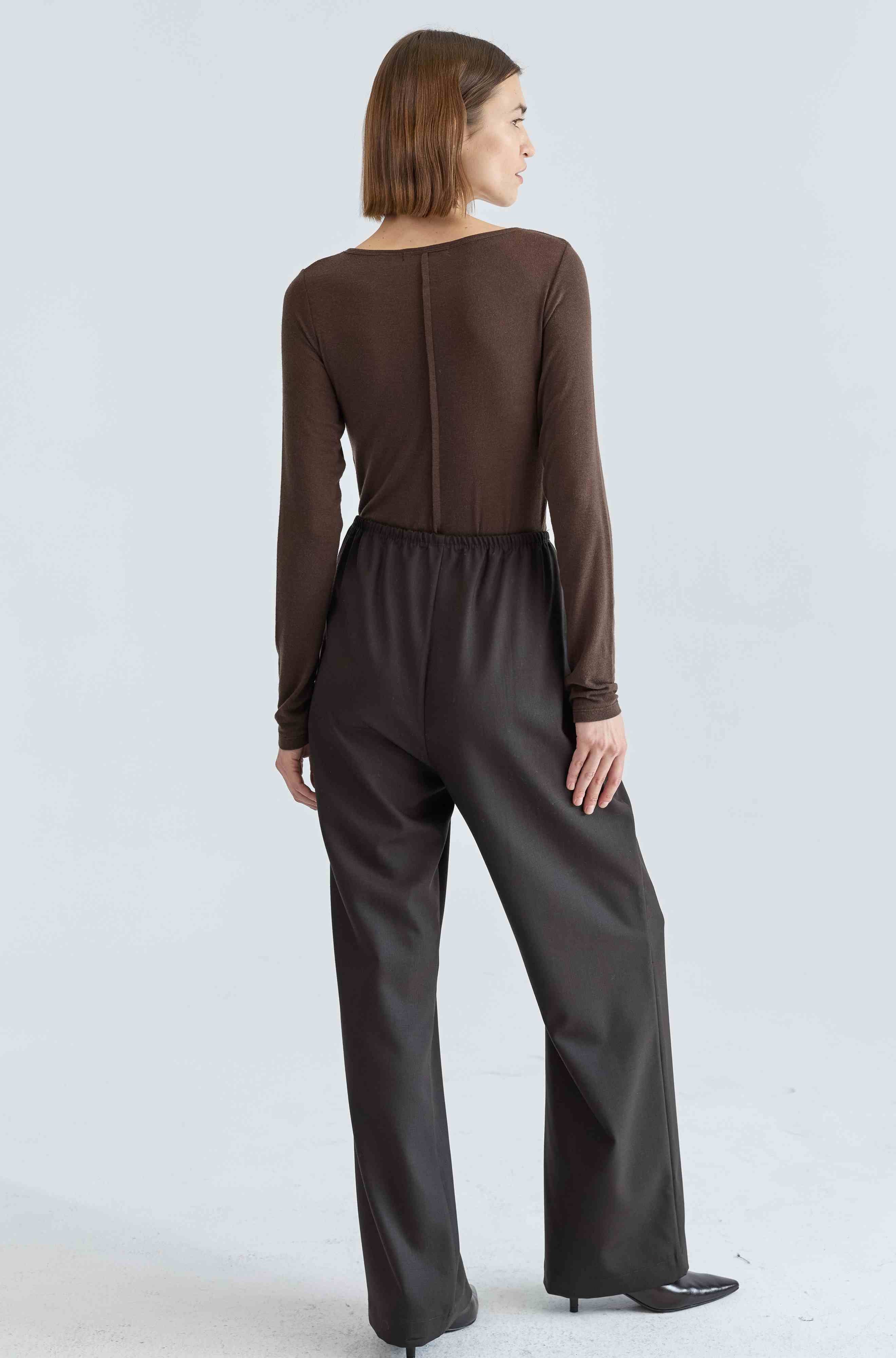 Woman wearing a brown long sleeve shirt and brown pants on a white background