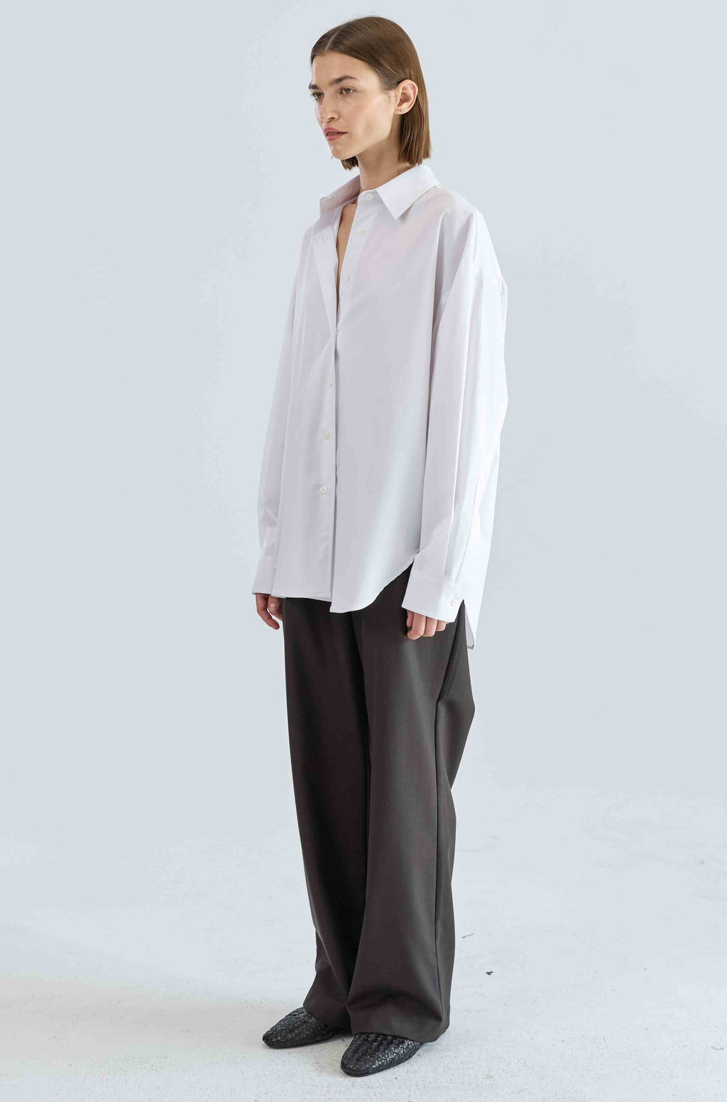 Person wearing a light-colored shirt and dark pants on a white background