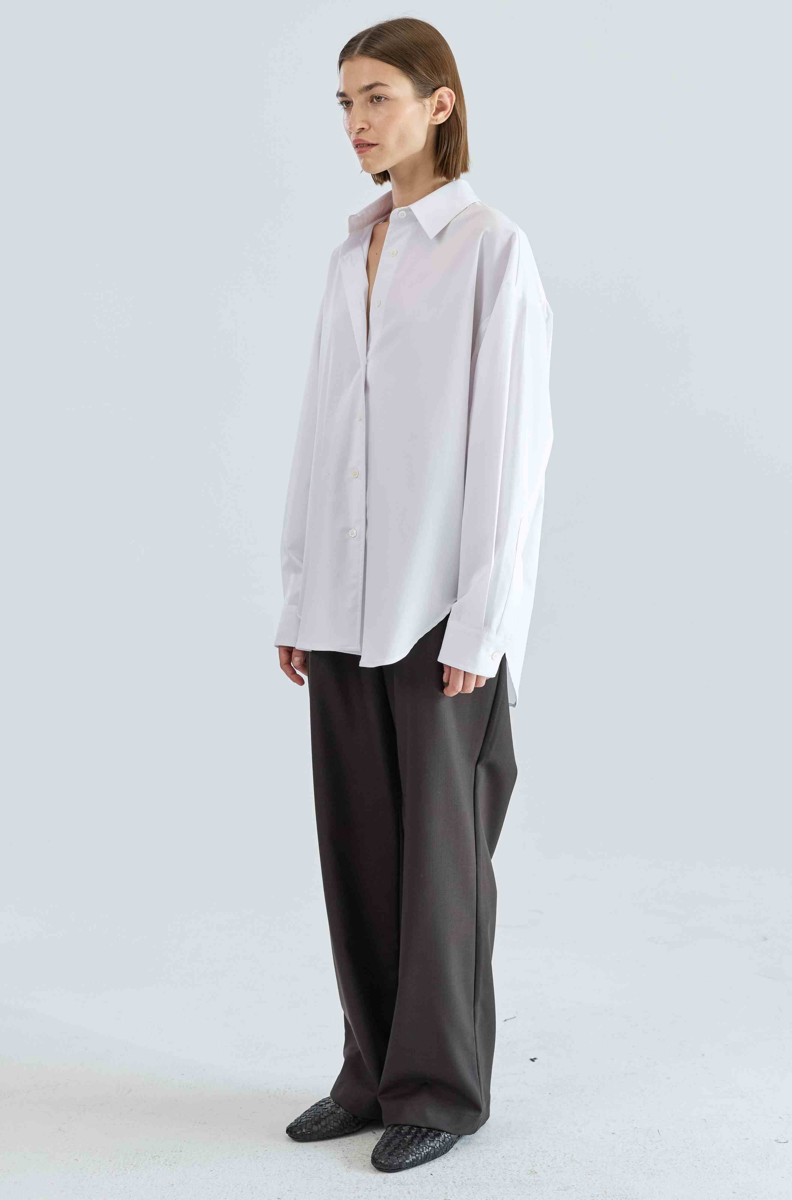 Person wearing a light-colored shirt and dark pants on a white background
