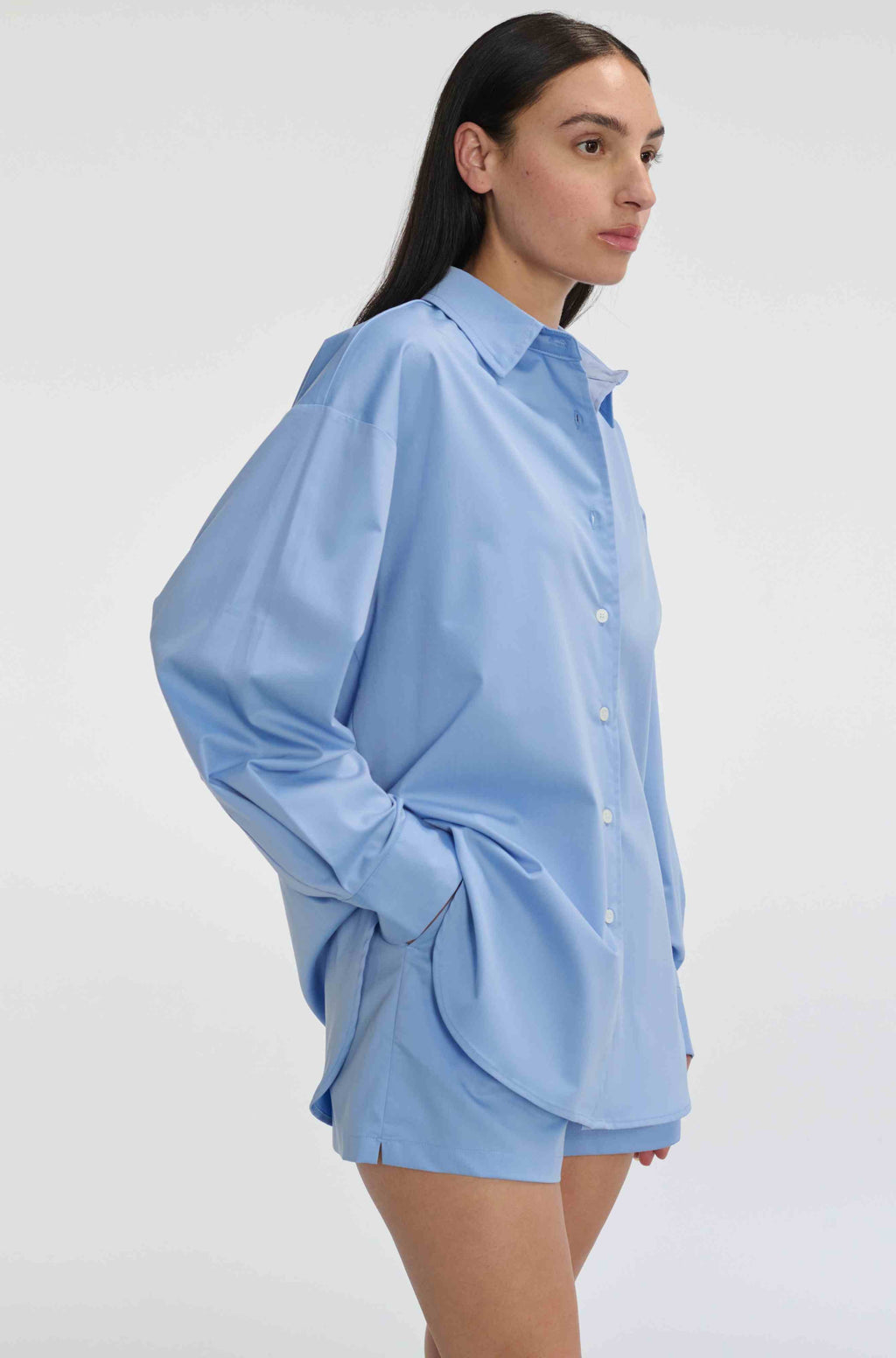 Woman wearing a light blue shirt and shorts on a white background