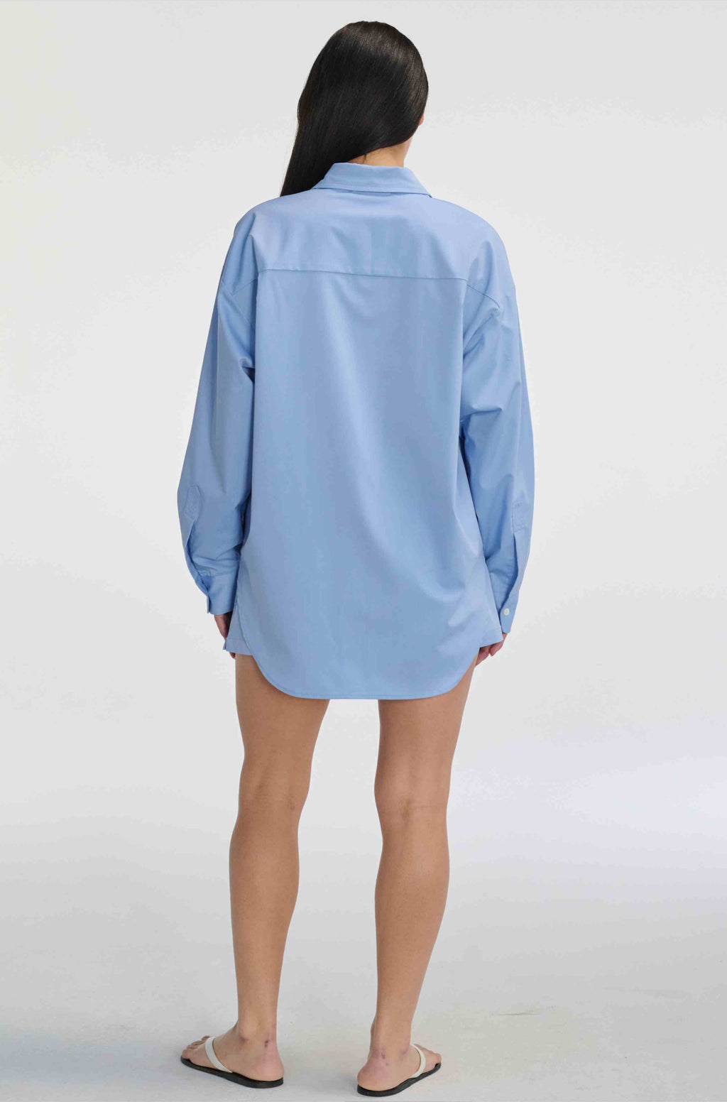Person wearing a light blue shirt against a white background