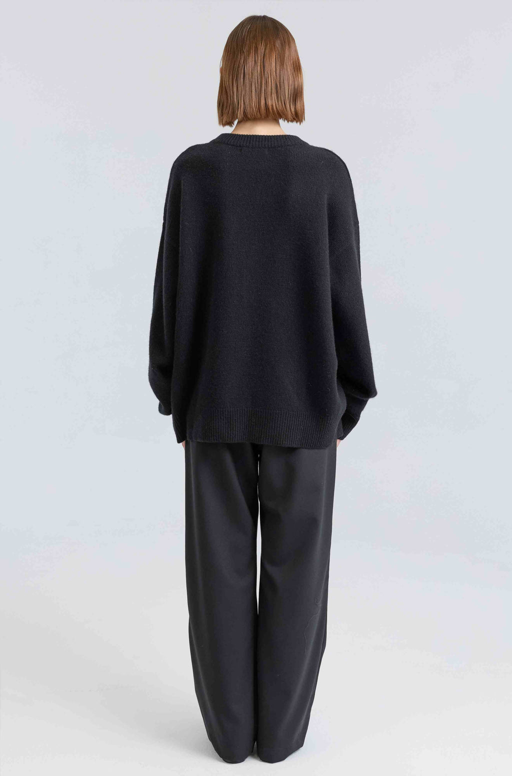Person wearing a black outfit on a light gray background