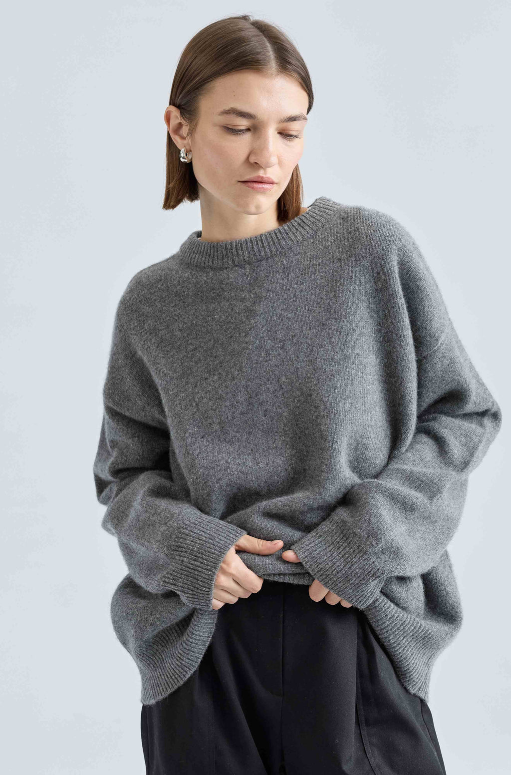 Woman wearing a gray sweater against a light blue background