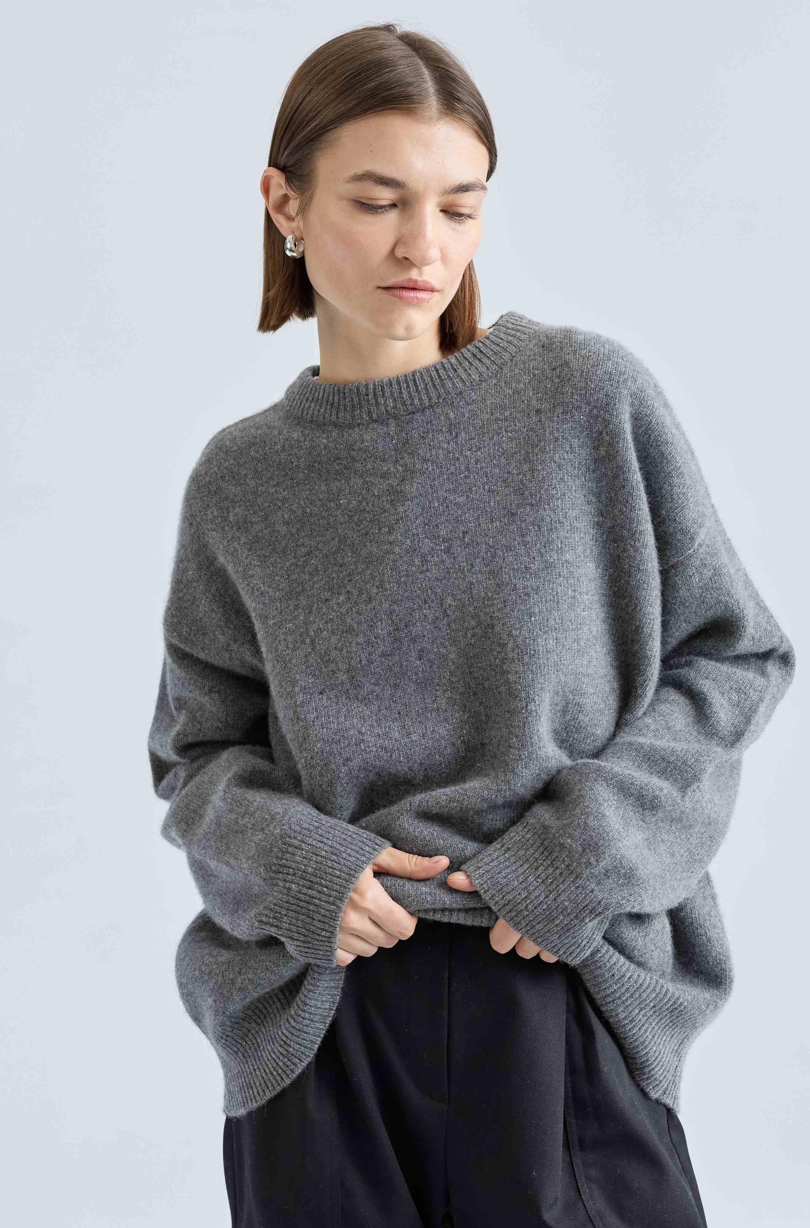 Woman wearing a gray sweater against a light blue background