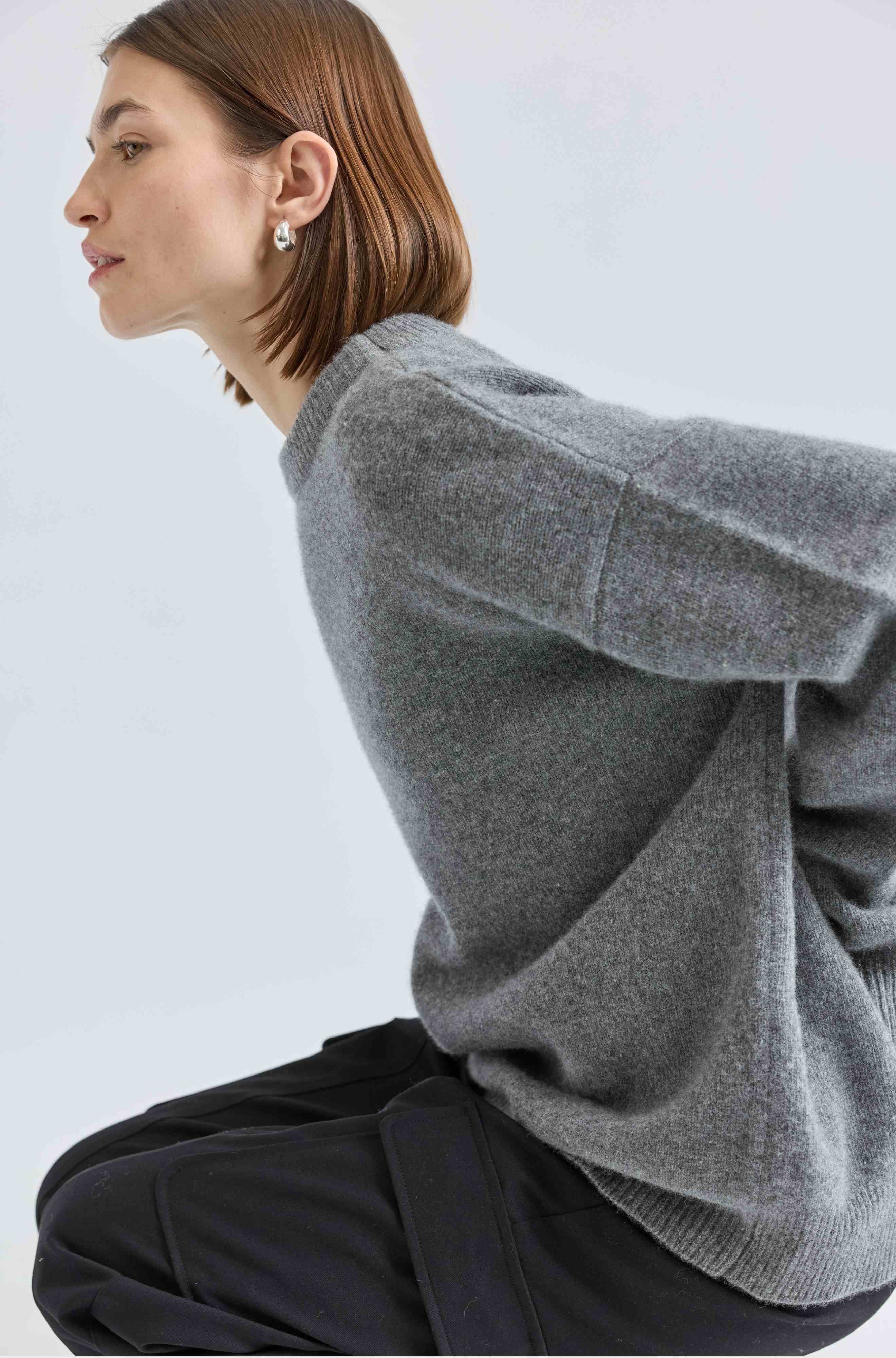 Person wearing a gray sweater against a light background