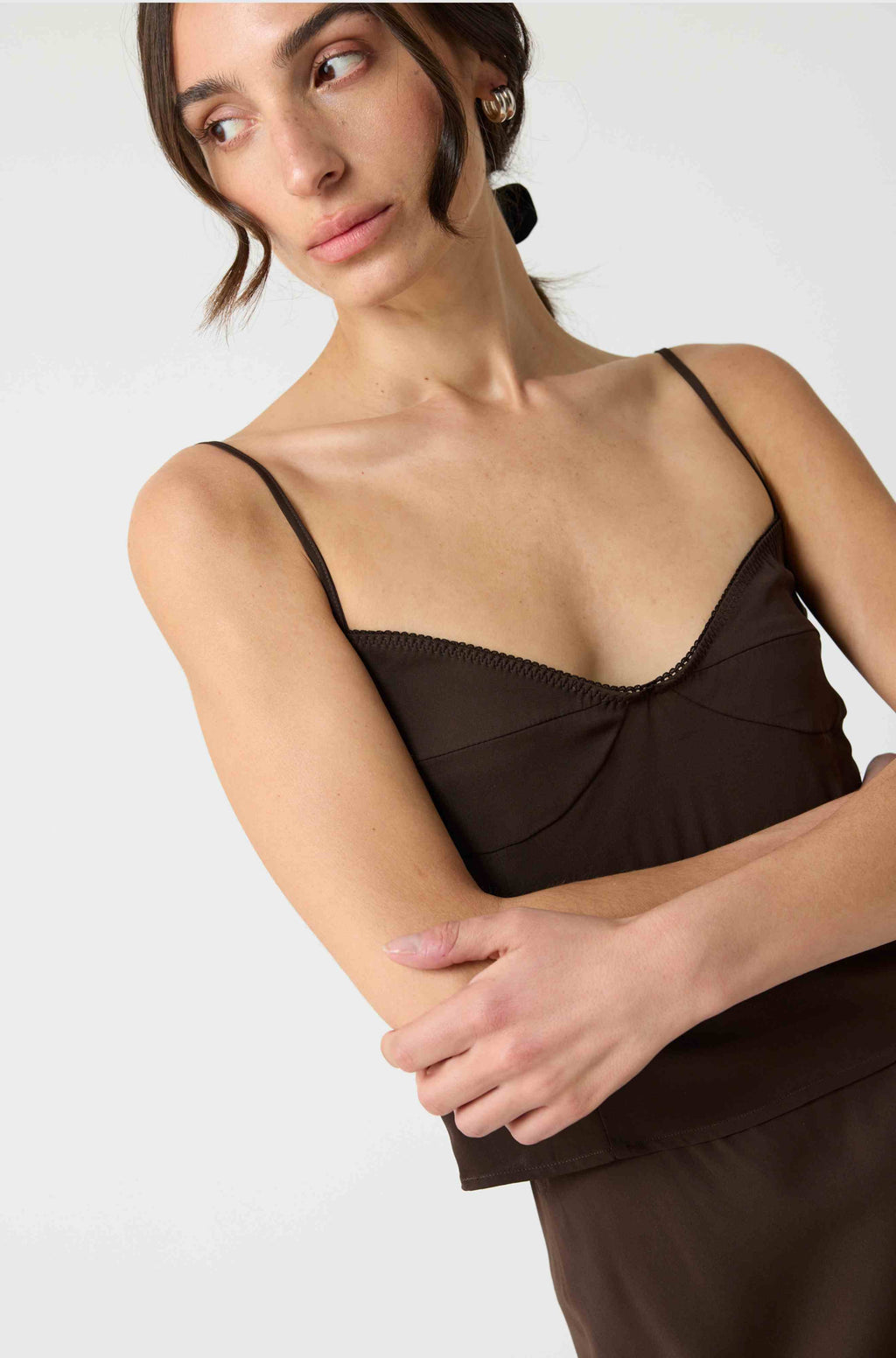 Woman wearing a silk brown top against a white background