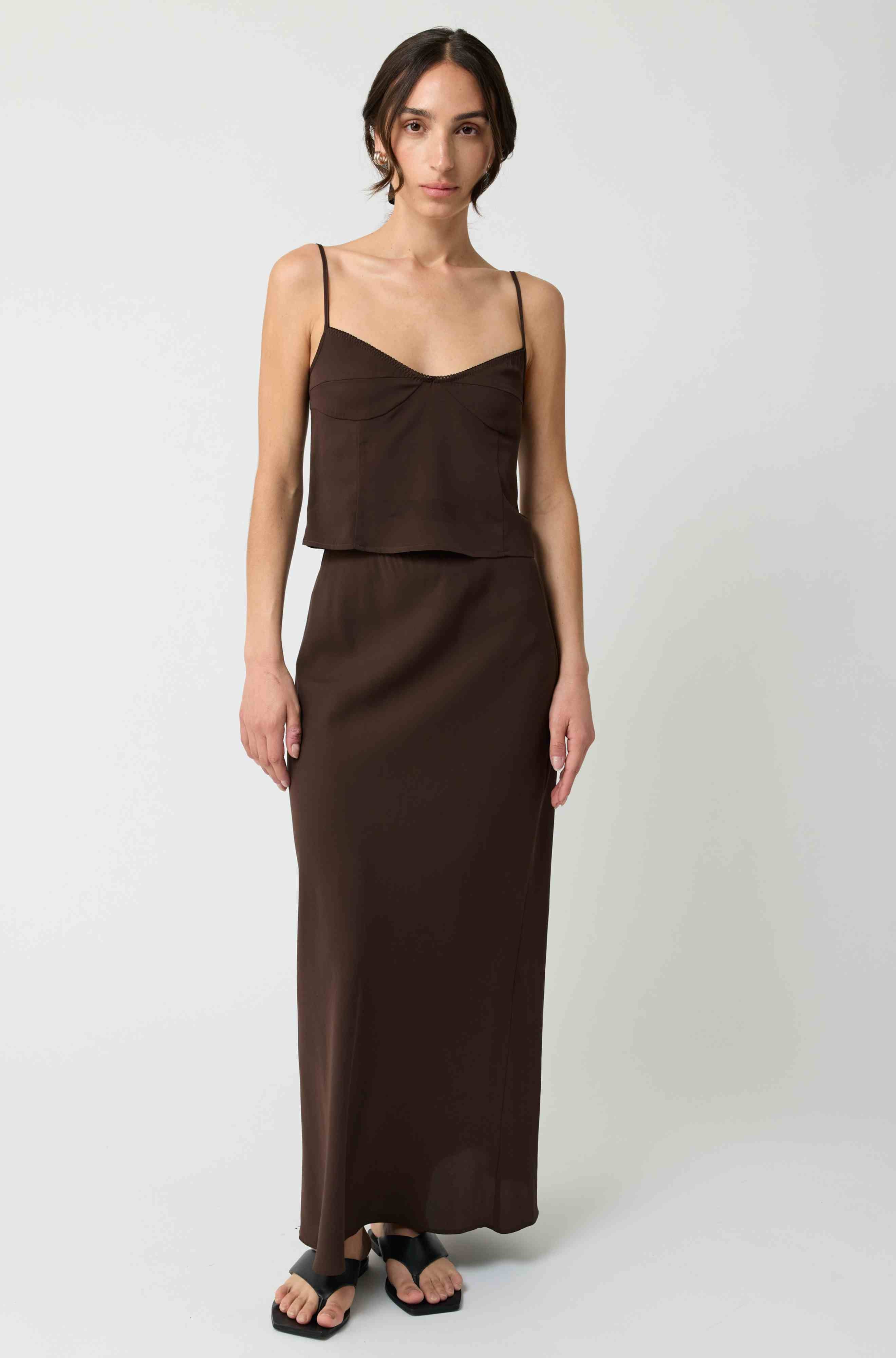 Woman wearing a brown silk set against a white background