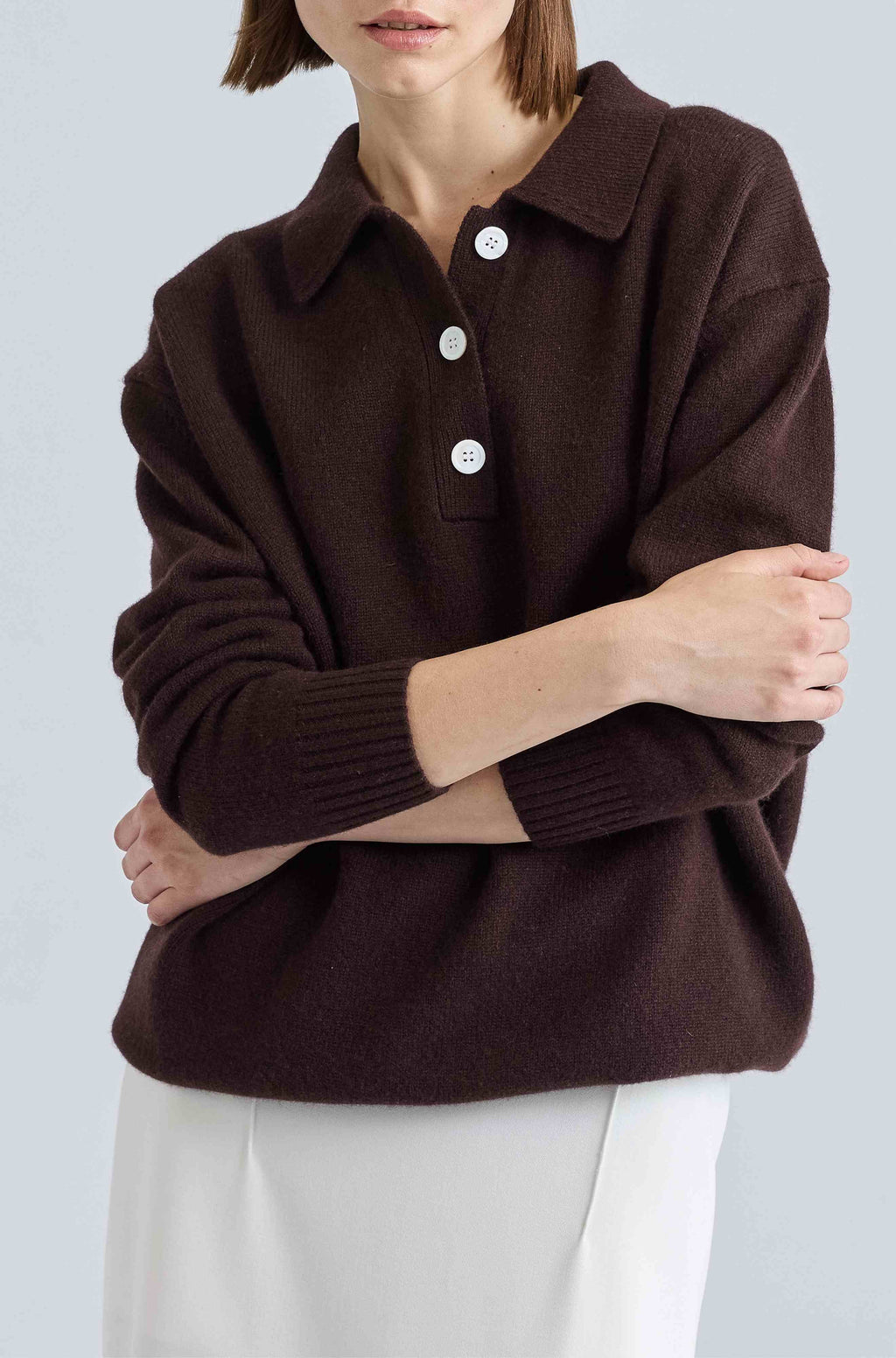 Person wearing a brown sweater with button details on a light gray background