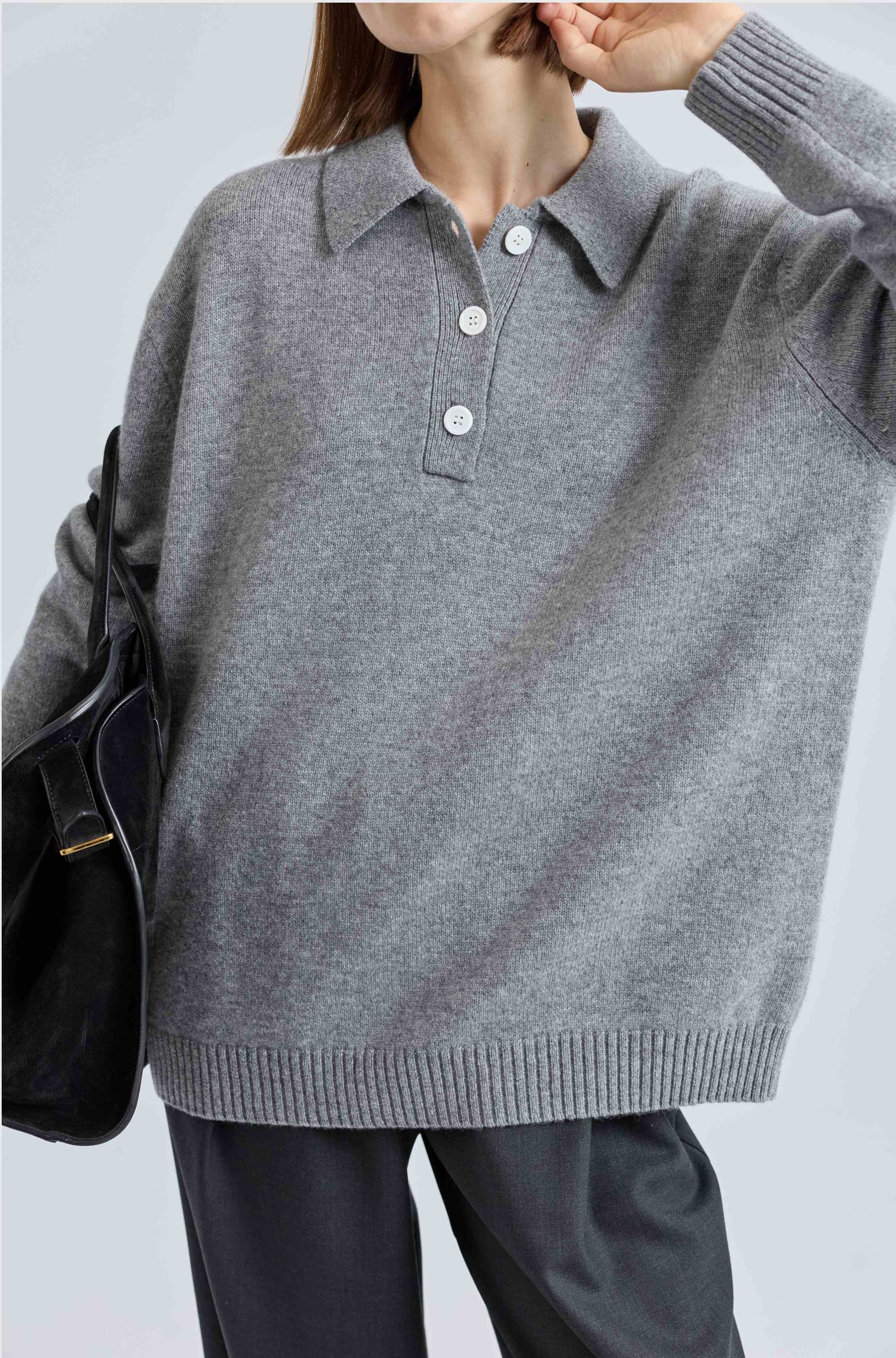 Person wearing a gray sweater with a collar on a light grey background