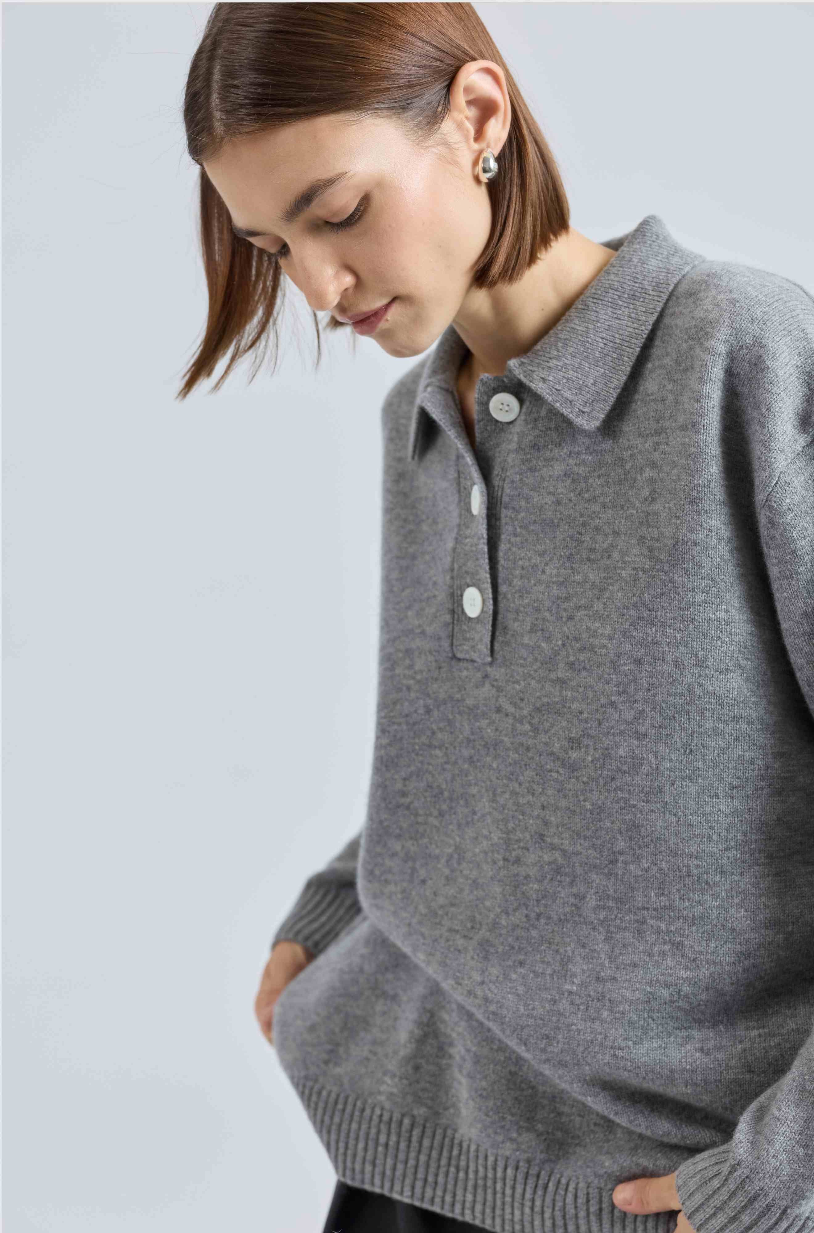 Woman wearing a gray sweater with a collar on a light gray background