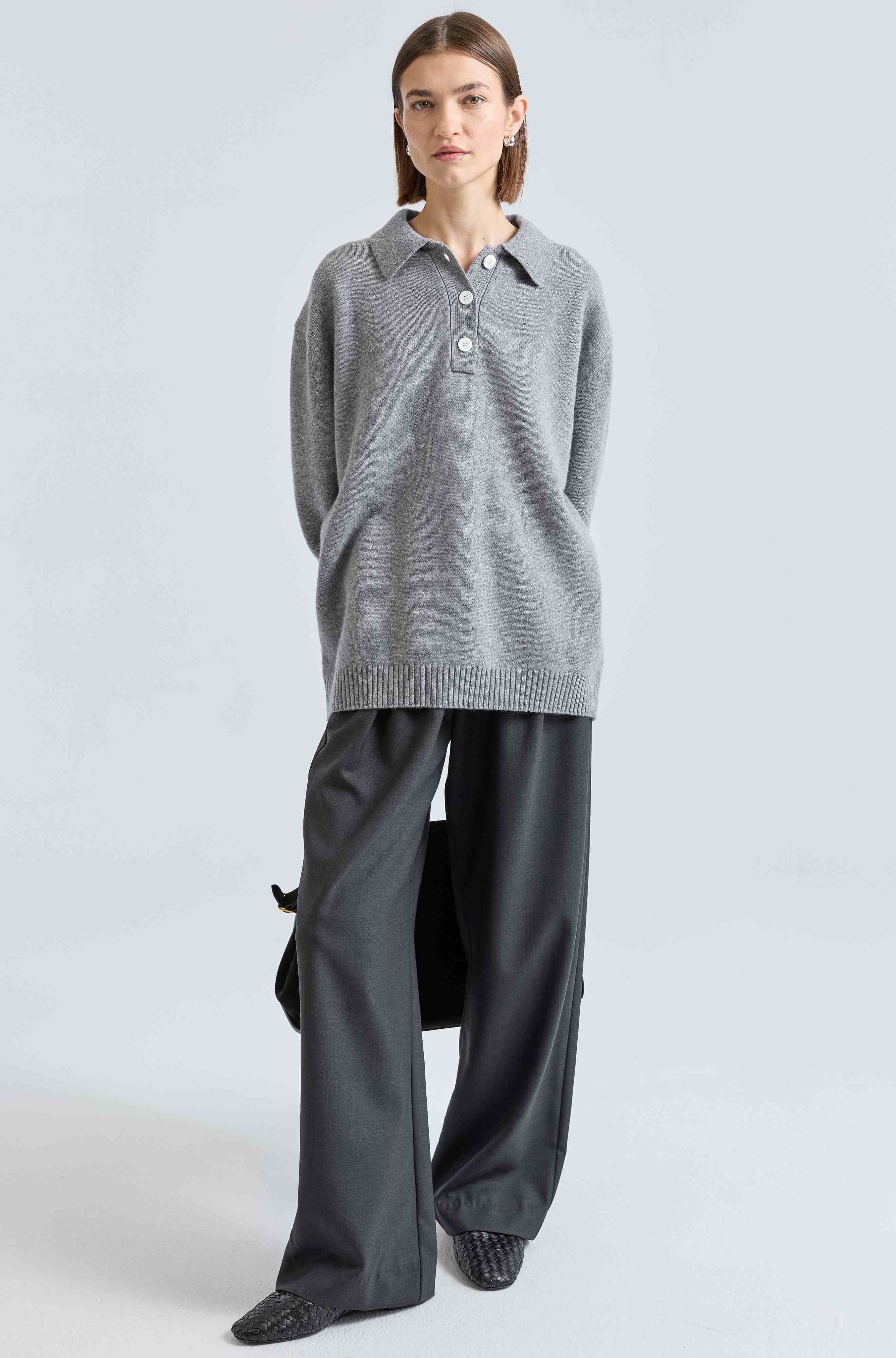 Person wearing a gray sweater and pants on a light gray background