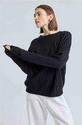 Woman wearing a black ribbed sweater and white pants