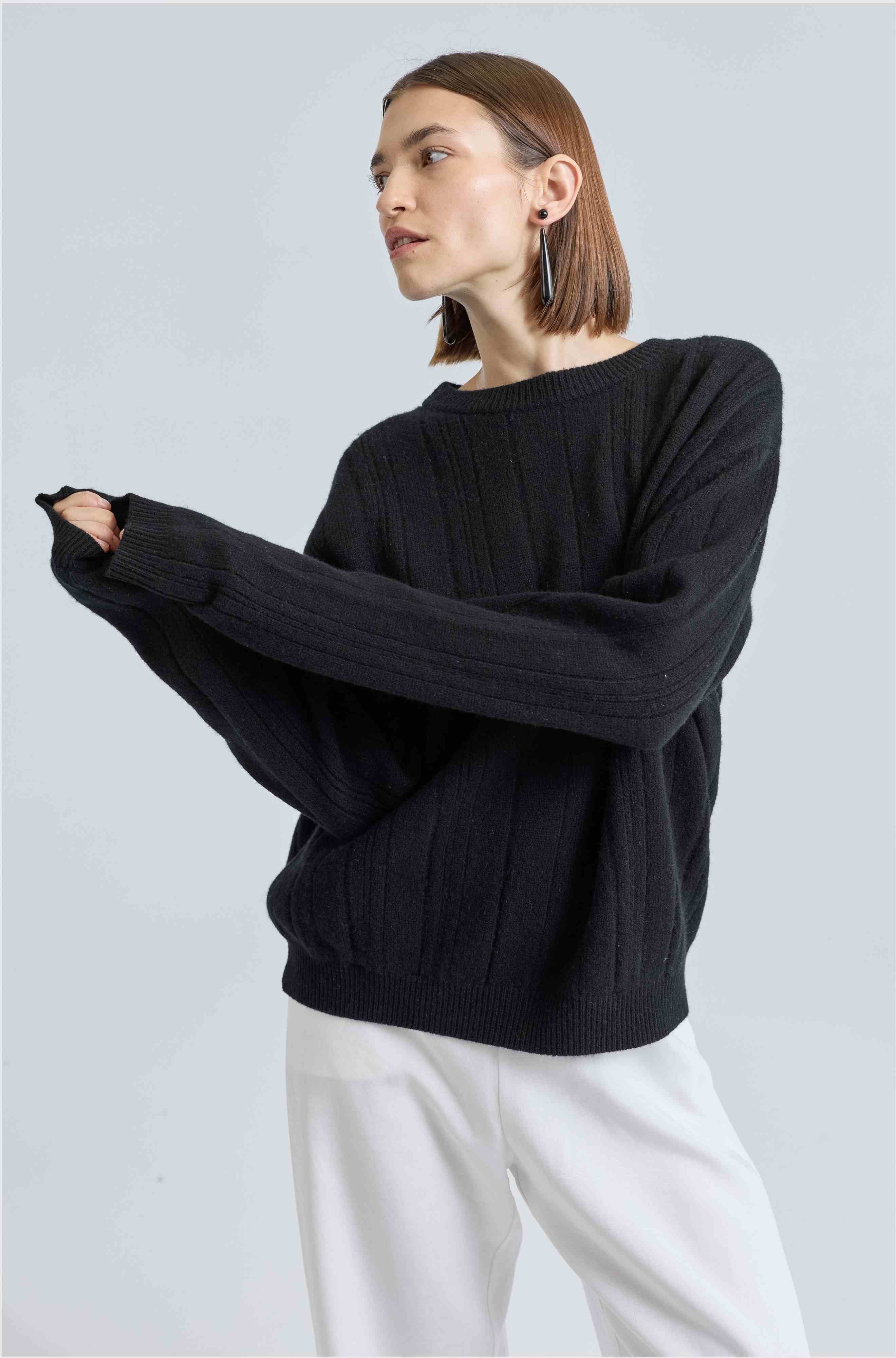 Woman wearing a black ribbed sweater and white pants