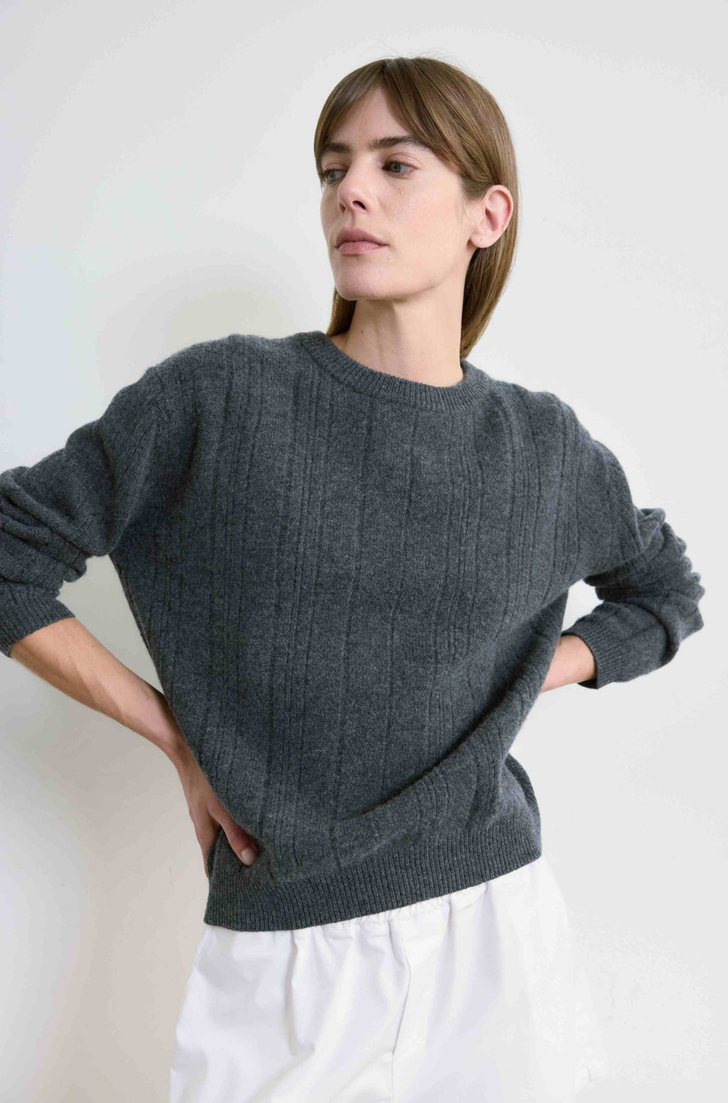 Woman wearing a gray sweater against a white background