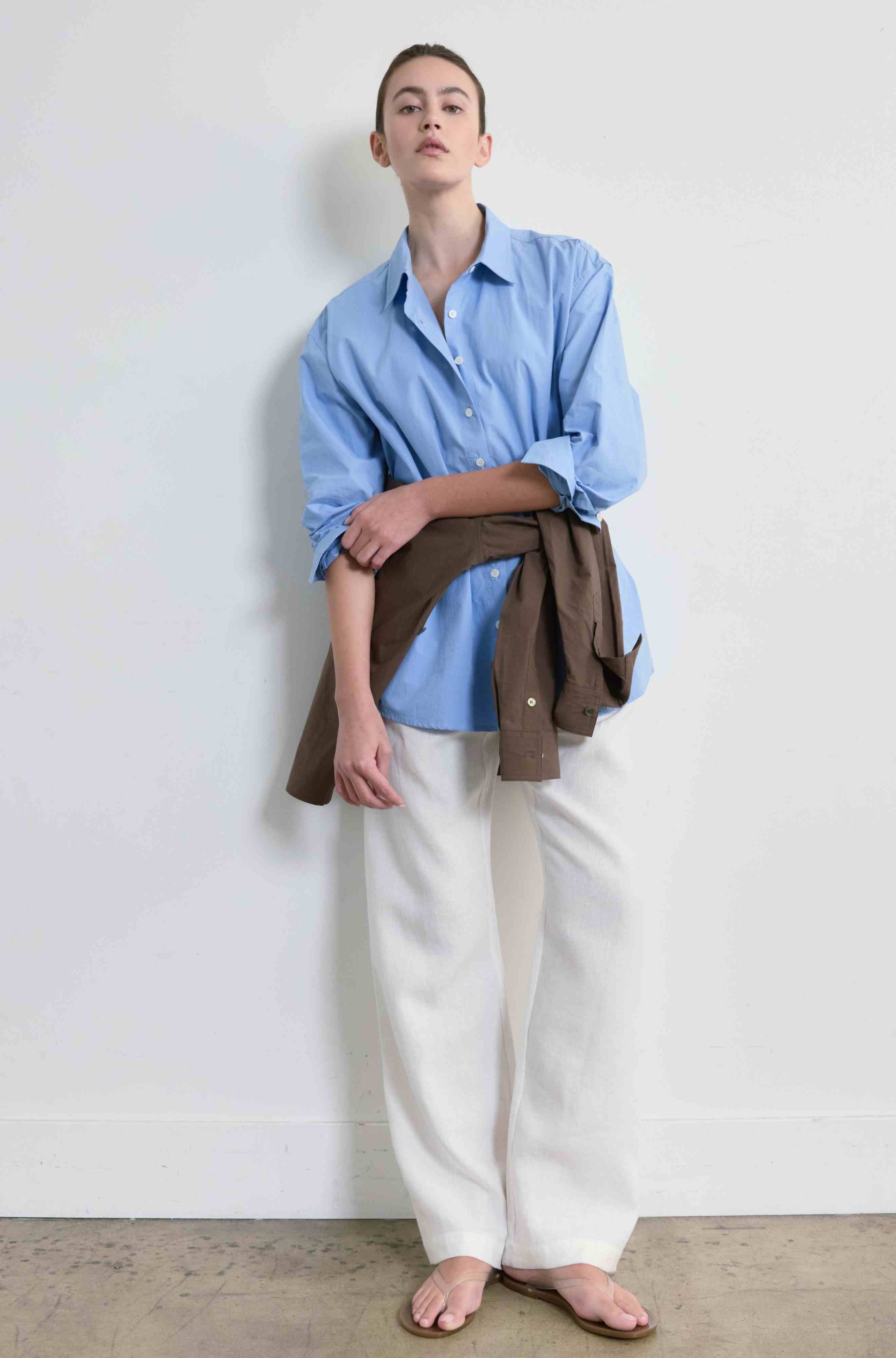 Person wearing a blue shirt and white pants against a plain background