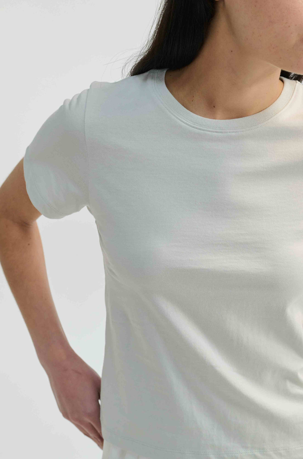 Person wearing a plain white t-shirt against a light gray background