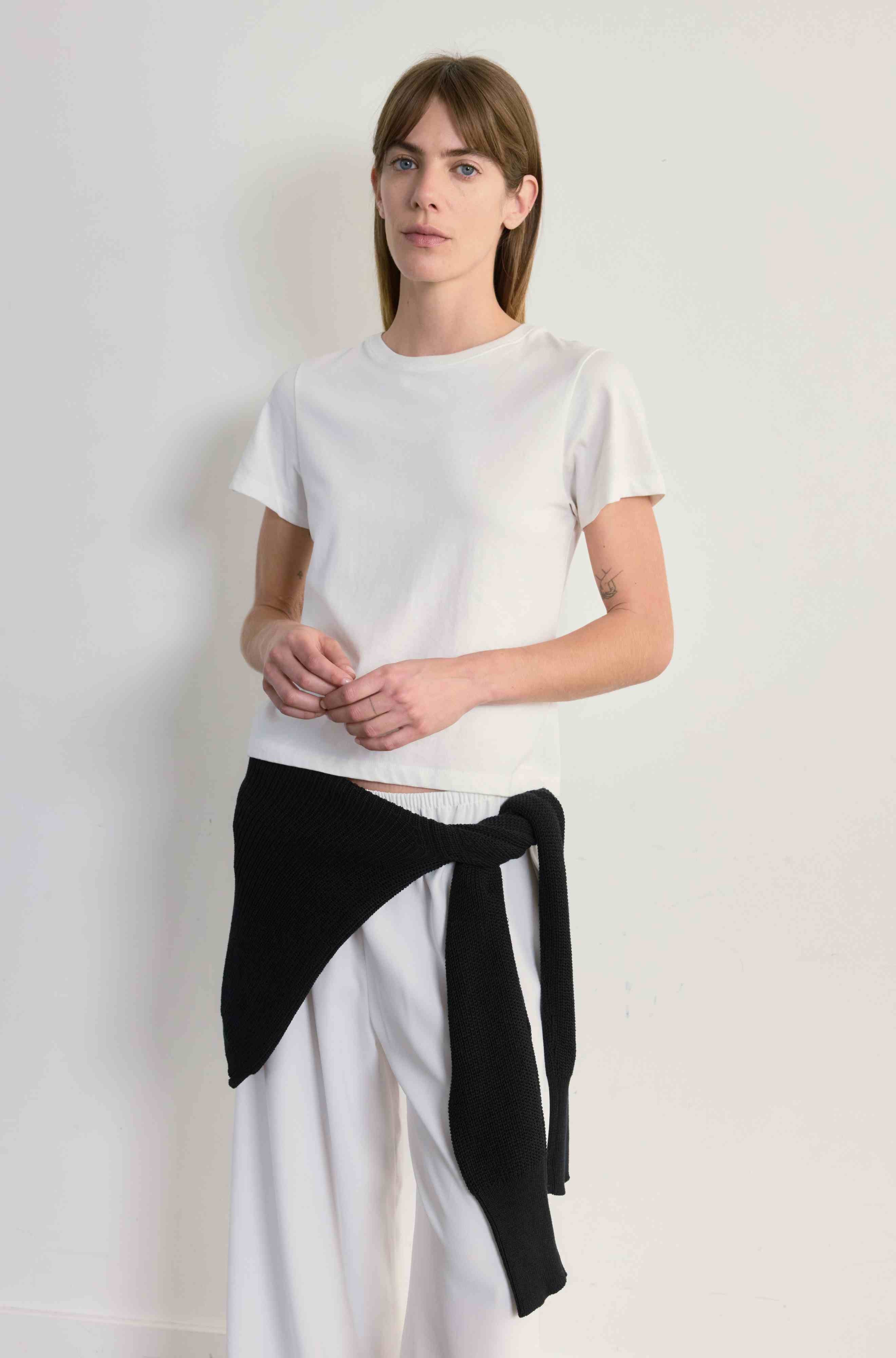 Person wearing a white t-shirt and white pants against a plain background