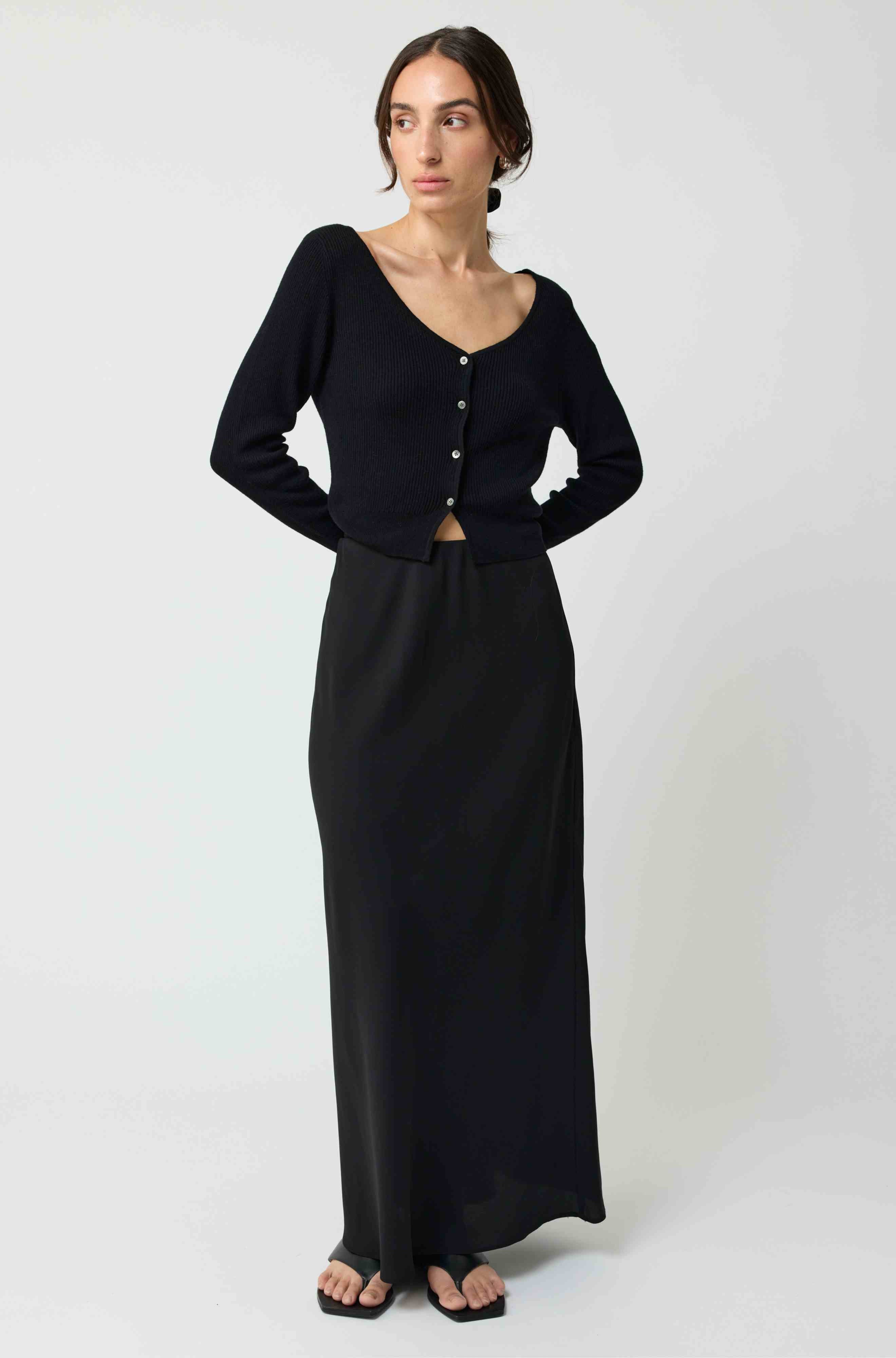 Woman wearing a black long skirt with a fitted bodice on a white background