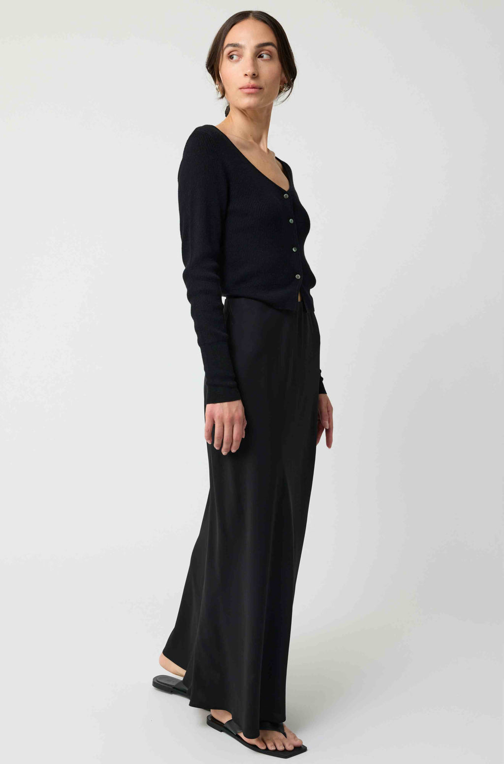 Woman wearing a black cardigan and black skirt on a white background