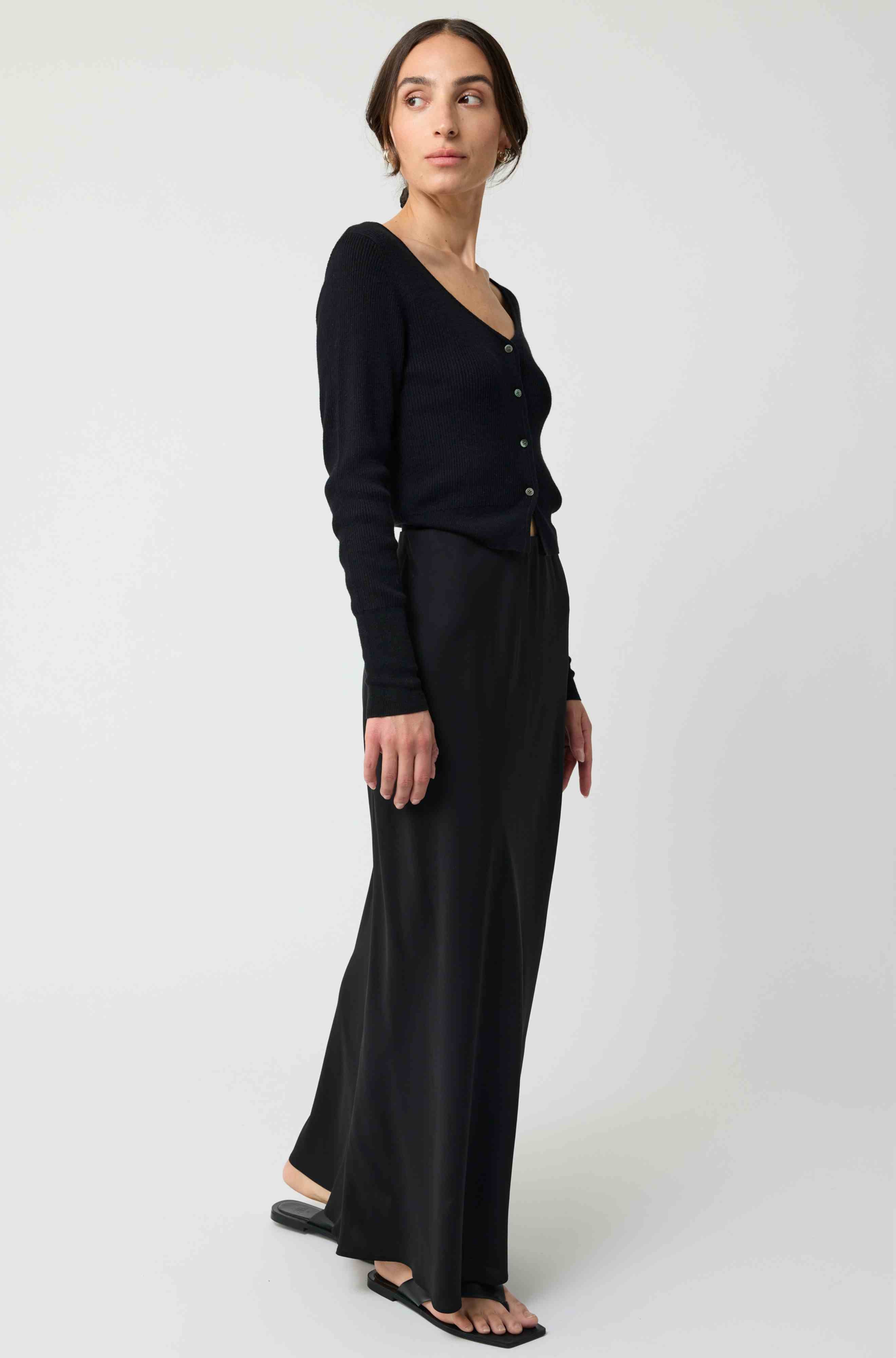 Woman wearing a black cardigan and black skirt on a white background