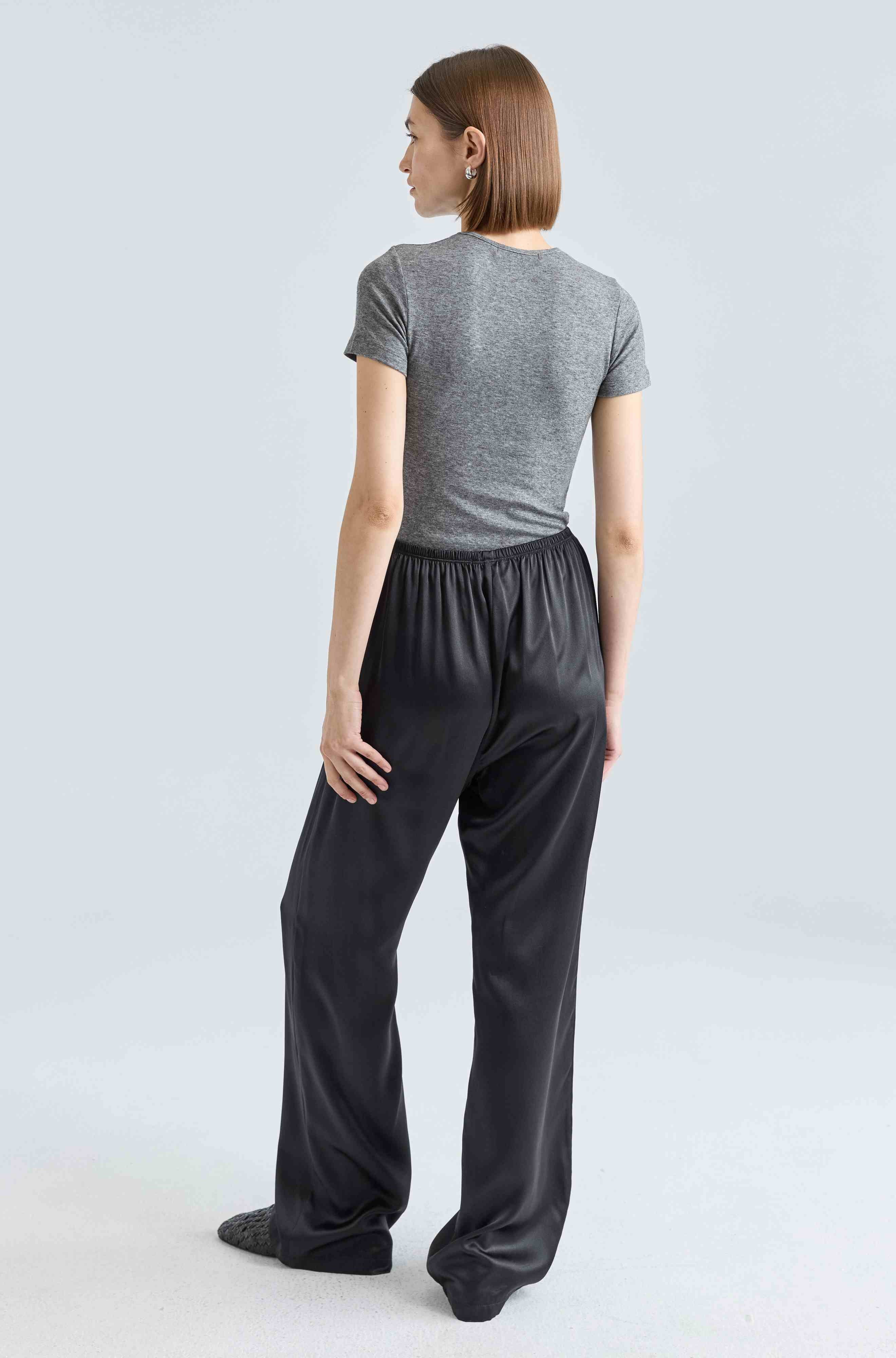 Person wearing a gray t-shirt and black pants on a light gray background