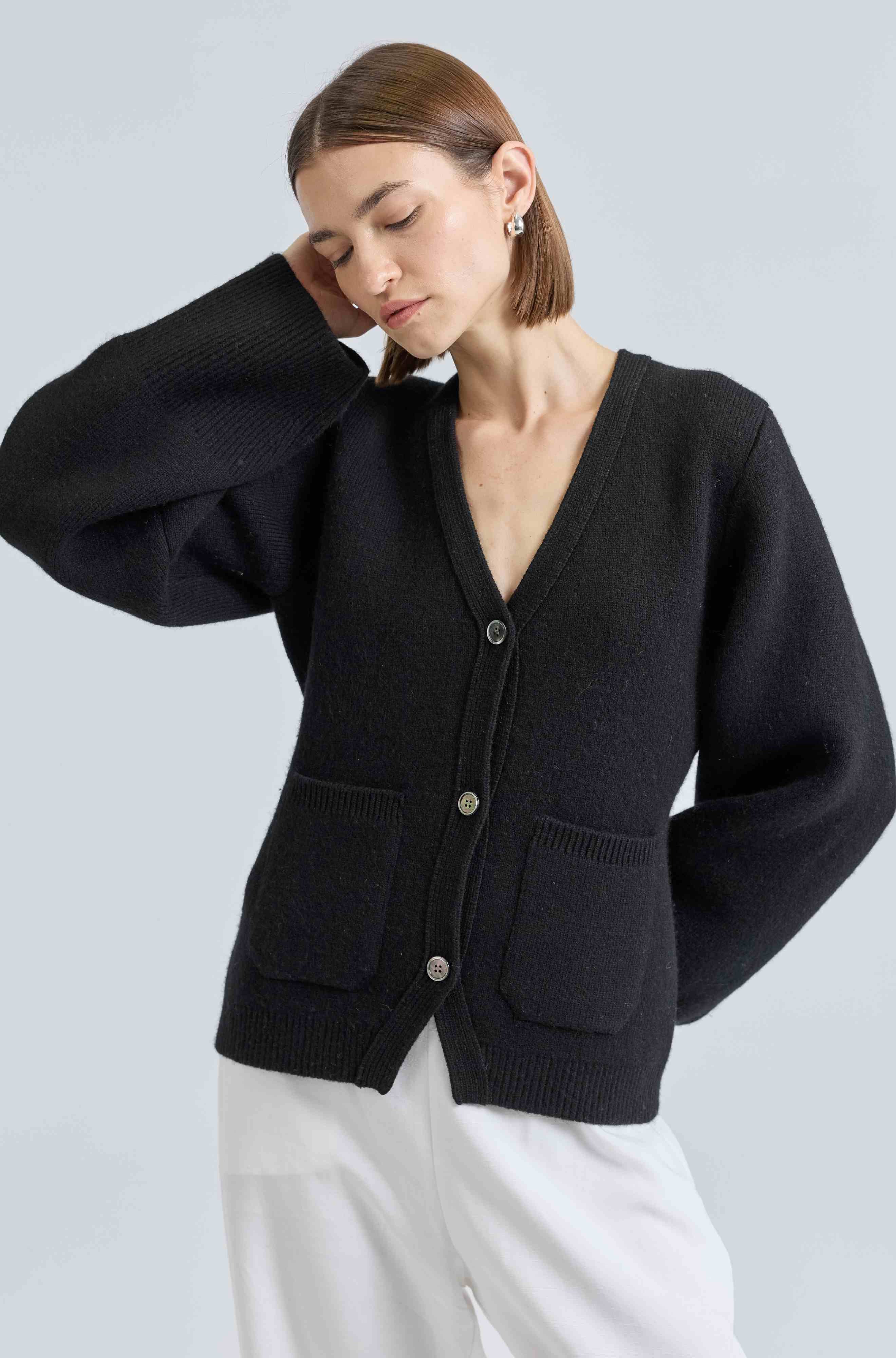 Woman wearing a black cardigan on a light gray background