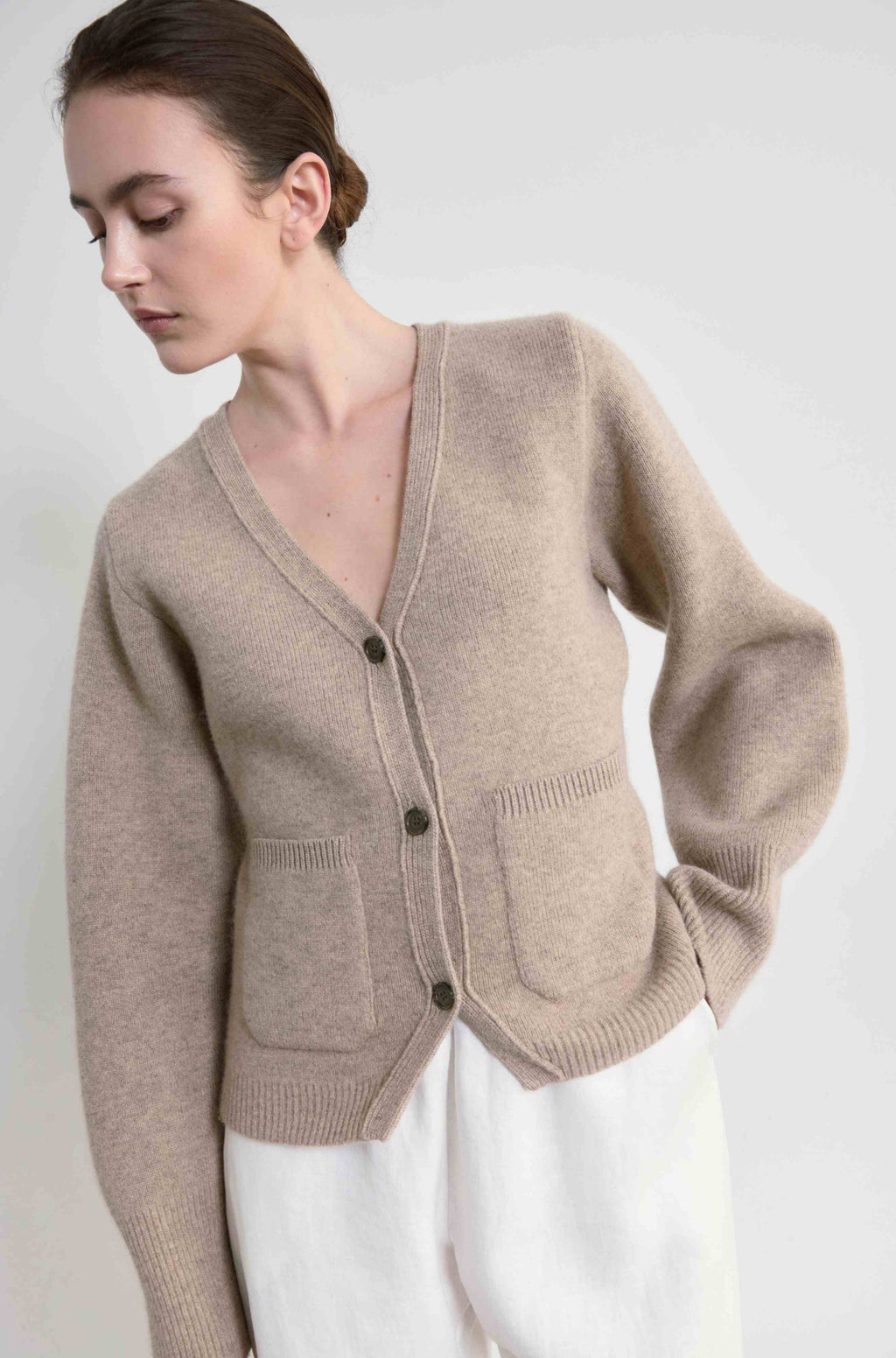 Woman wearing a beige cardigan against a white background