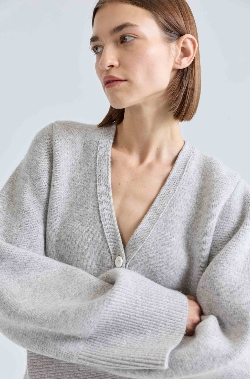 Woman wearing a light gray cardigan against a plain background